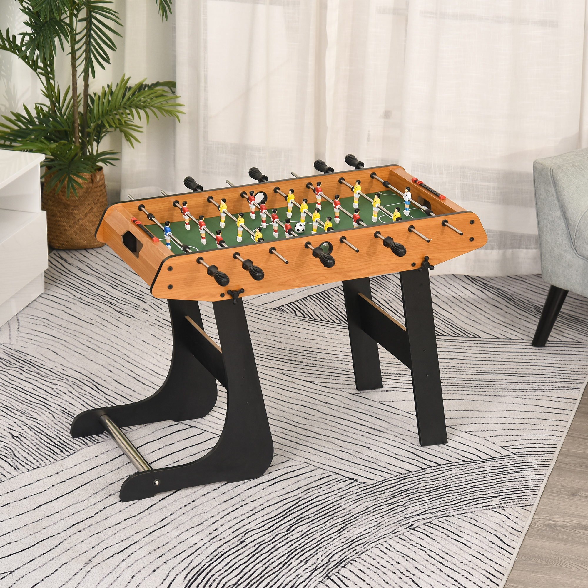 Mesa de futbolín con jugadores, campo verde y marco de madera.