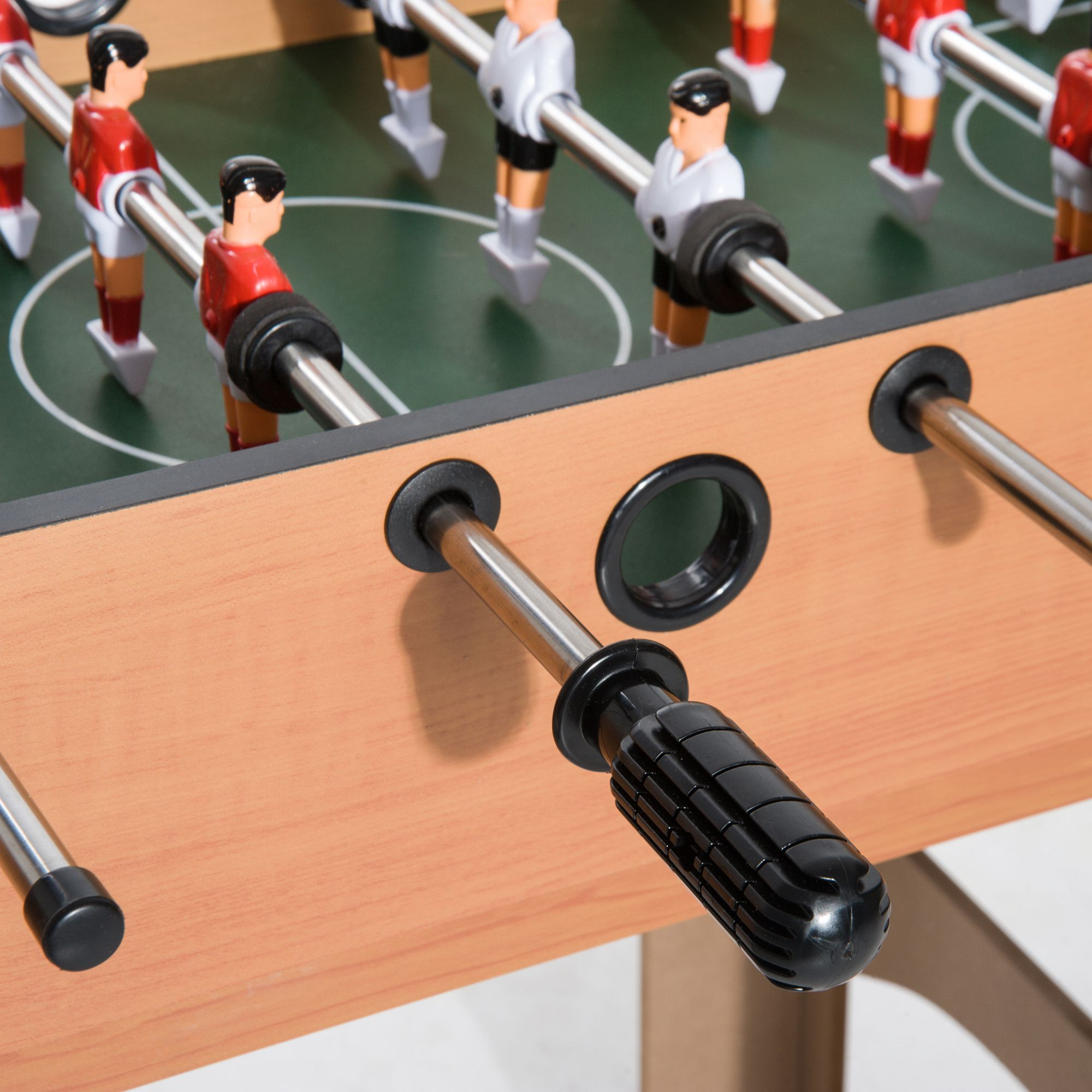 Calcio balilla, primo piano delle maniglie e dei giocatori, con un campo da gioco verde visibile.
