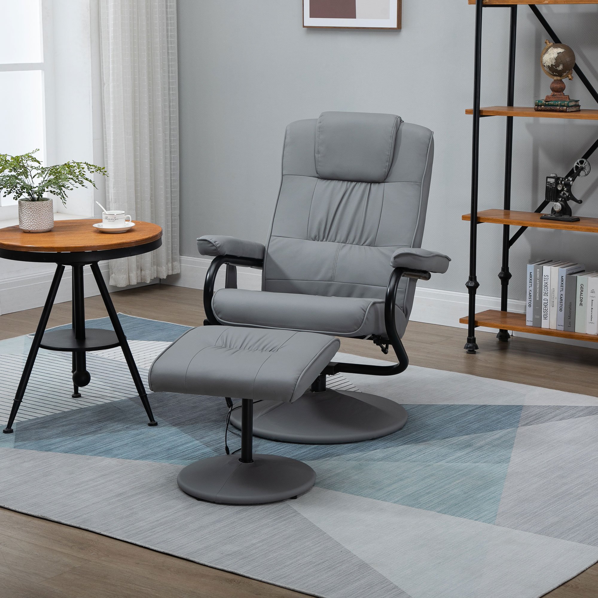 Una silla reclinable gris con reposapiés, junto a una mesita y una estantería.