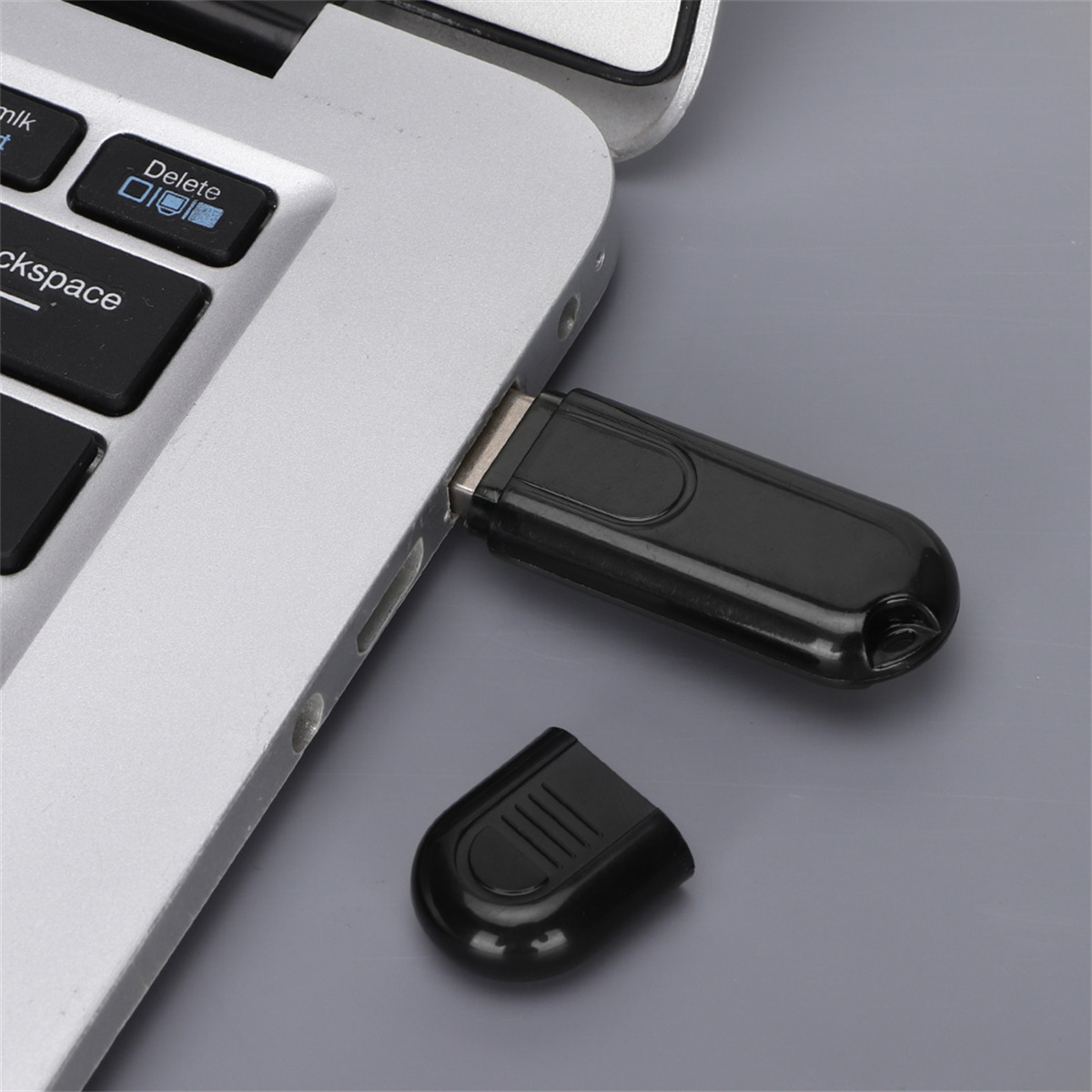 Schwarzer USB-Bluetooth-Adapter, der in einen Laptop eingesteckt ist.