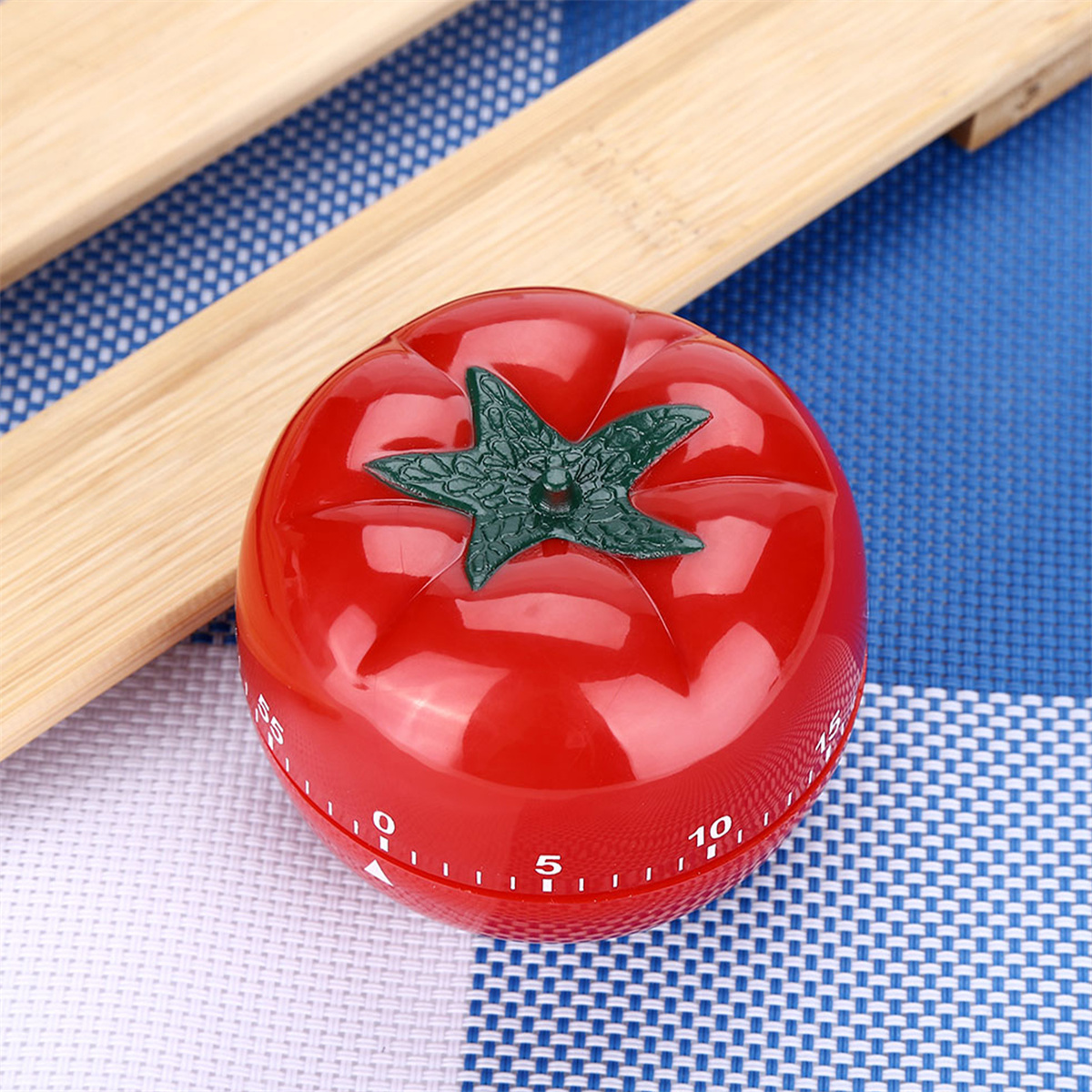 Ein roter tomatenförmiger Küchentimer auf einer blau-weiß karierten Oberfläche.