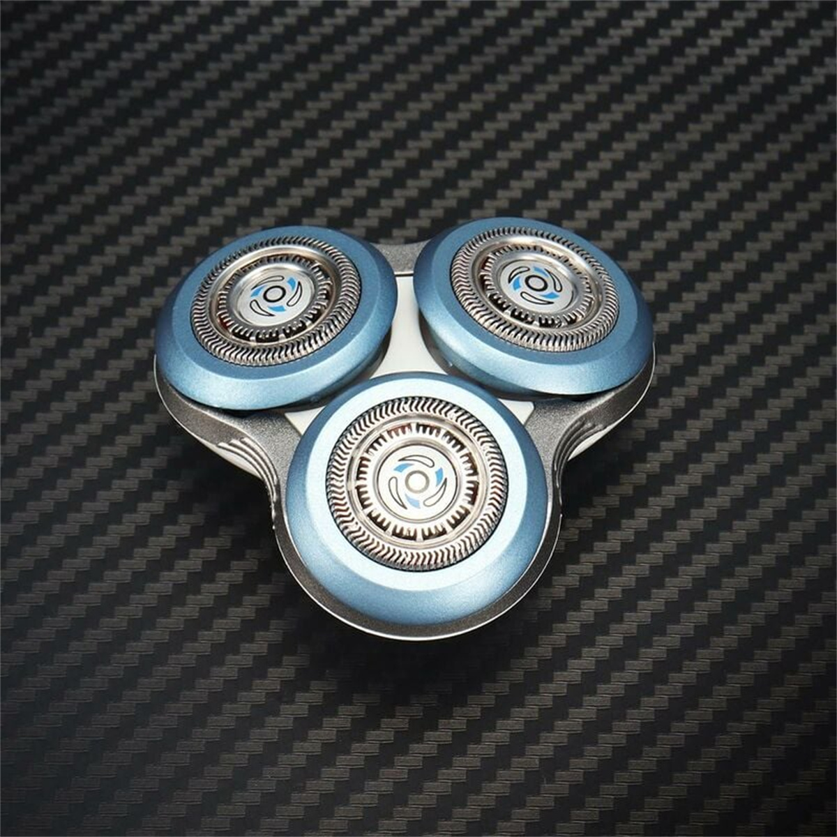 Nahaufnahme eines Rasierkopfes mit drei blauen, kreisförmigen Klingen auf dunkler, strukturierter Oberfläche.