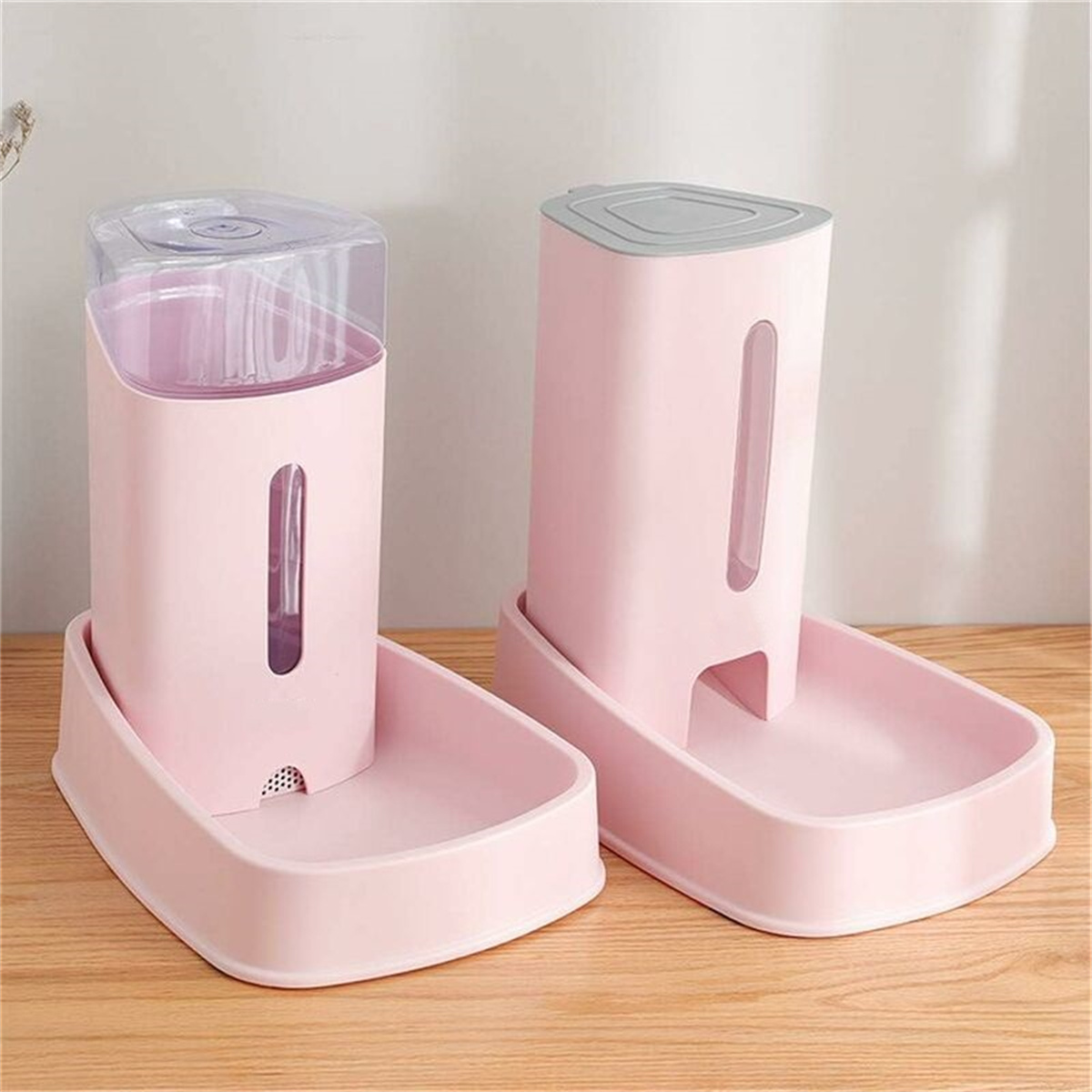 Zwei rosa Haustier-Wasserspender auf Holz. Einer hat einen klaren Deckel.