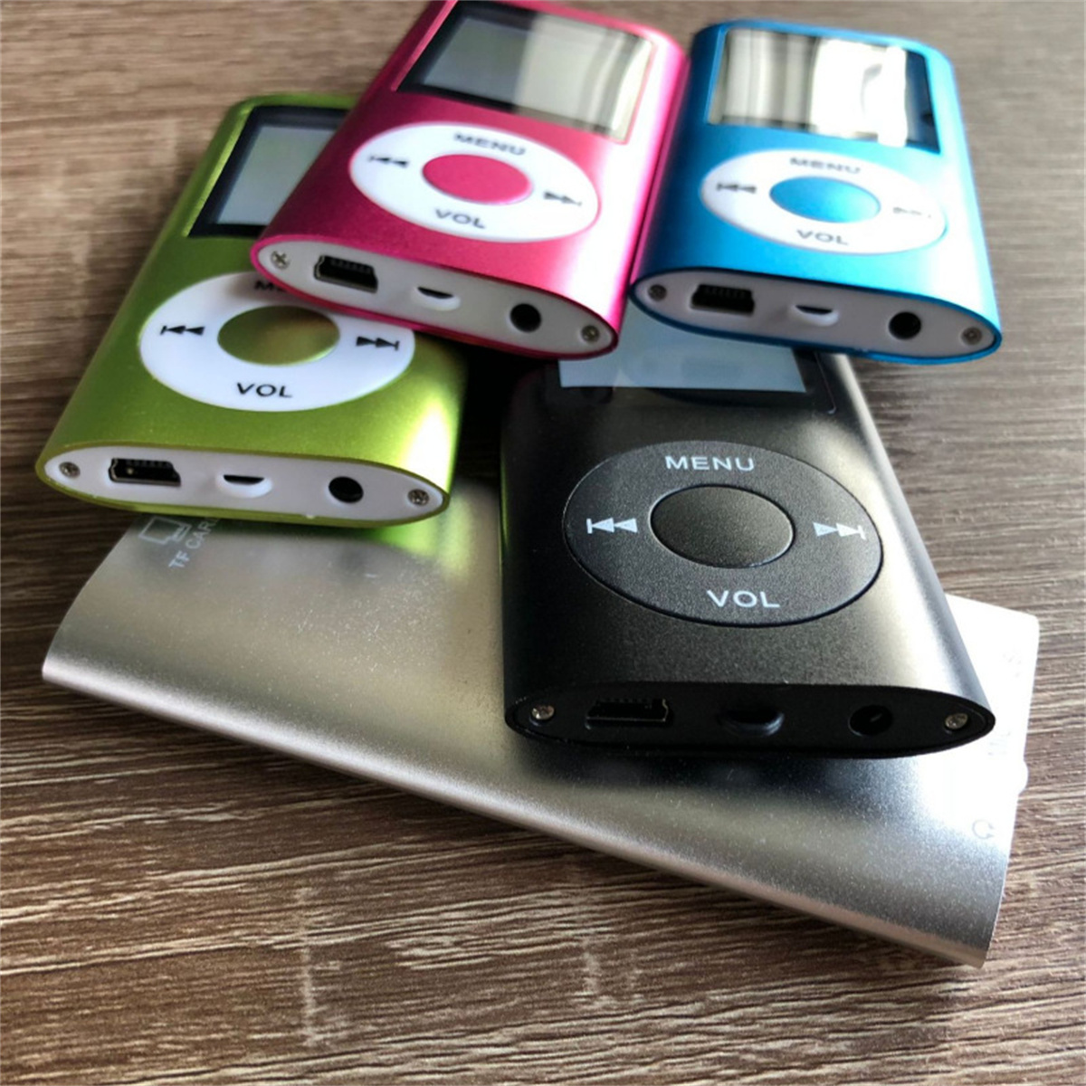 Vier MP3-Player in Grün, Pink, Blau und Schwarz. Sie befinden sich auf einer silbernen Ladestation.