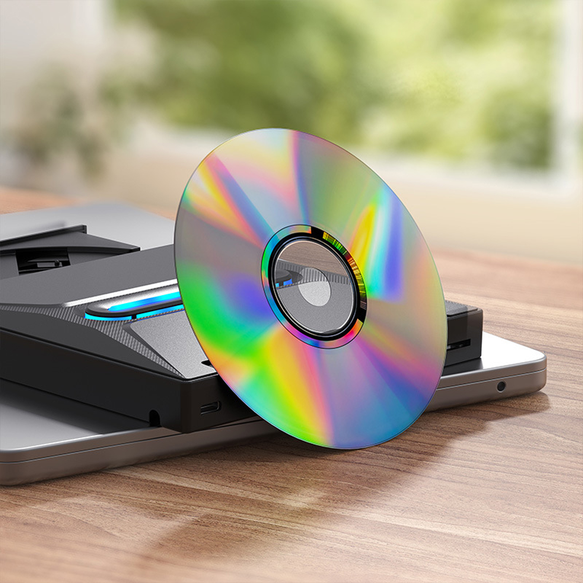 CD auf einem Laptop, der Regenbogenfarben reflektiert, und ein schwarzer DVD-Player.