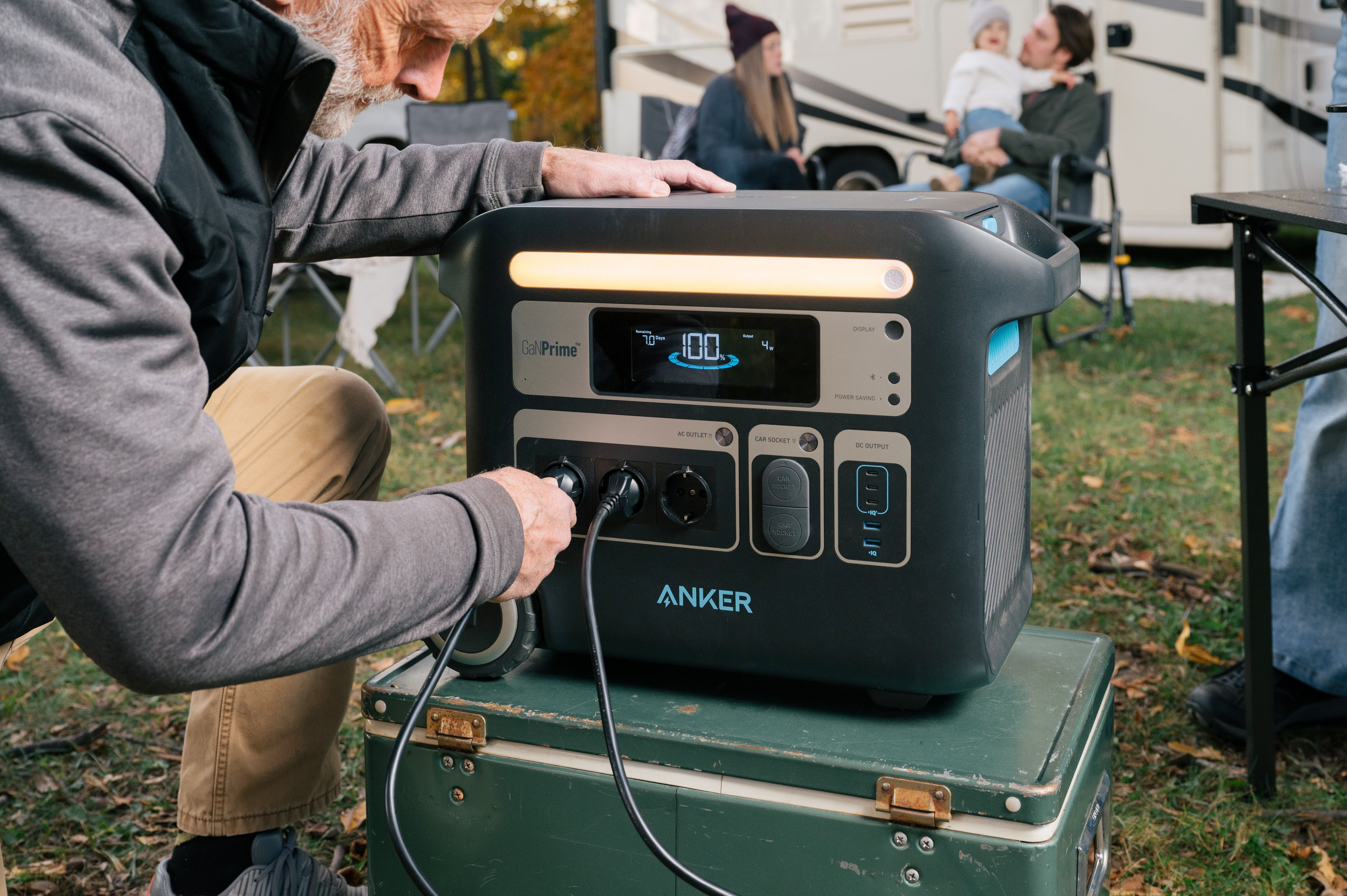 Mężczyzna podłączający przewód zasilający do czarno-niebieskiej przenośnej stacji zasilania.
