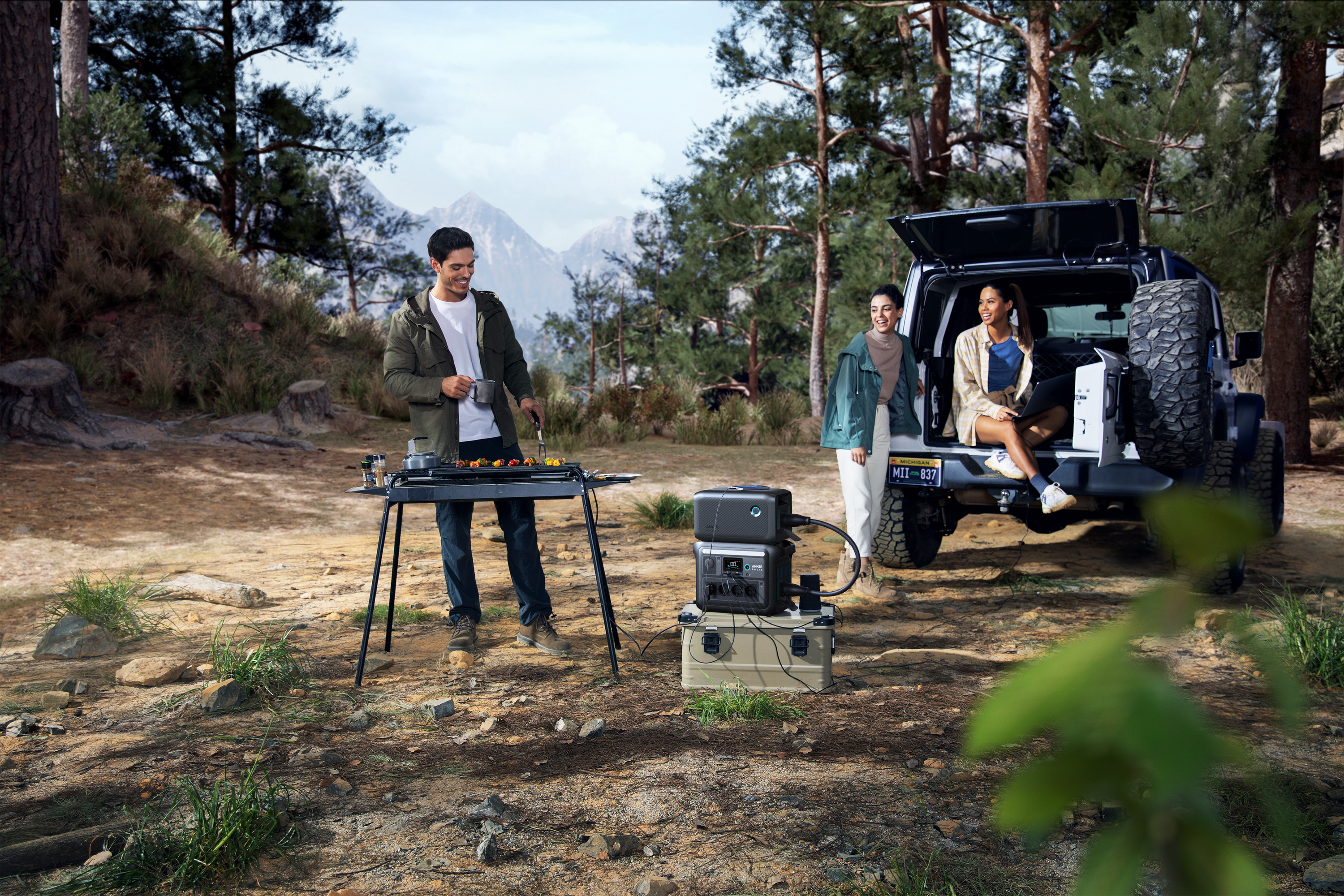 Trzy osoby grillują jedzenie obok samochodu, w leśnym otoczeniu.