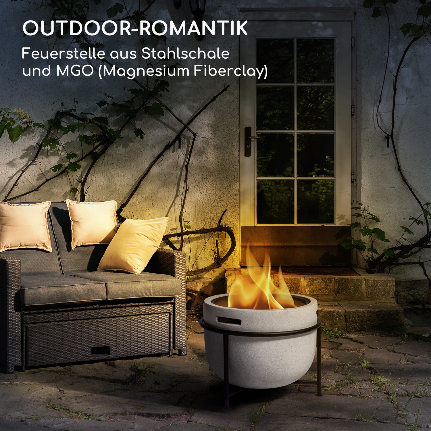 Feuerstelle im Freien mit Flammen, umgeben von Sofa und Kissen, neben einer weißen Tür.