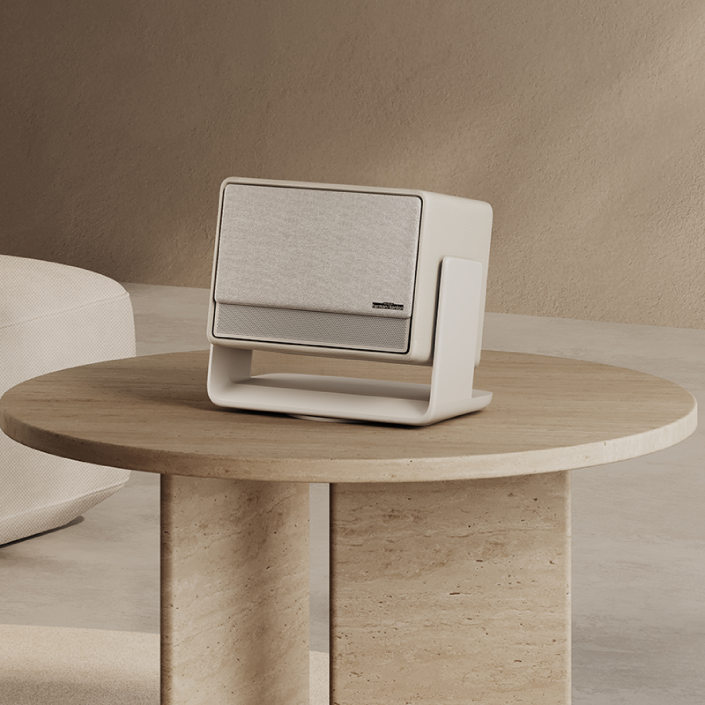 Biały głośnik na beżowym stoliku, z beżowym tłem i jasnobeżowym krzesłem.