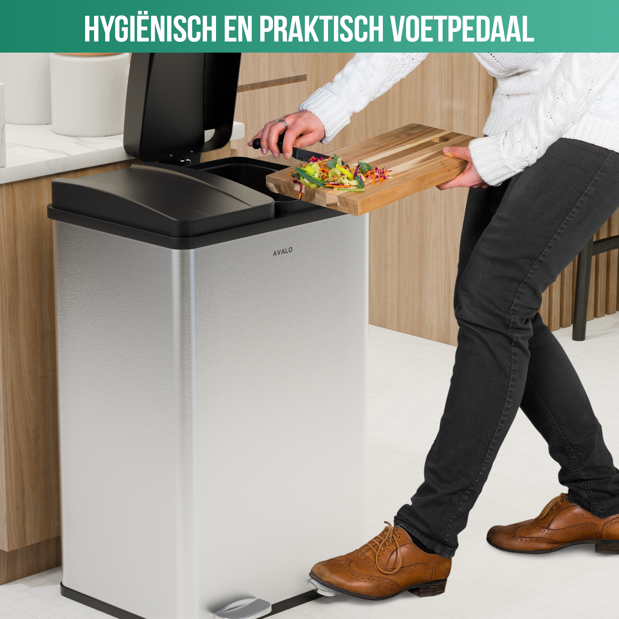 A person is using a foot pedal on a silver trash can, holding a wooden cutting board with food scraps.