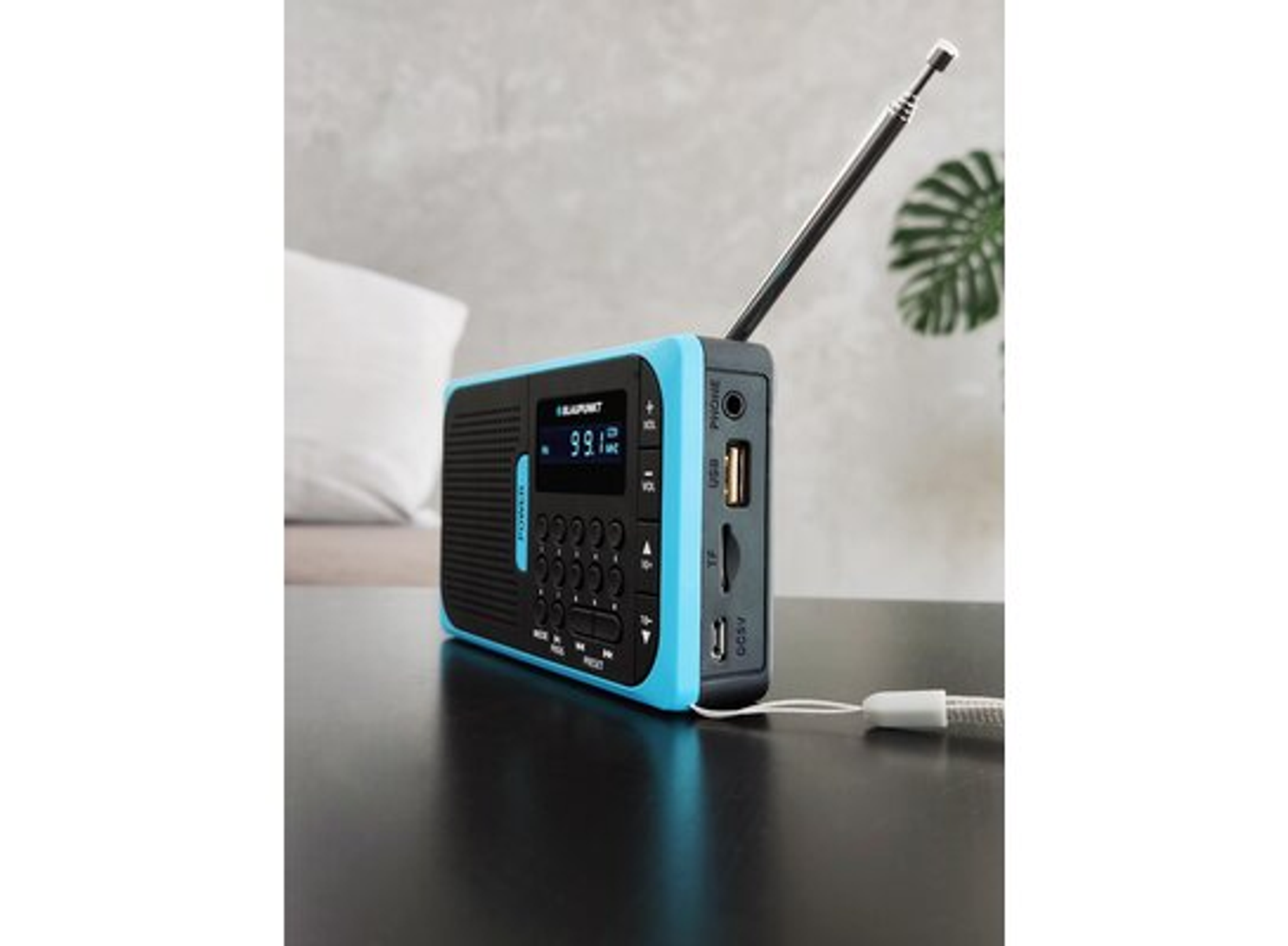 Radio blu e nera su una superficie scura. Ha un display, pulsanti e antenna.