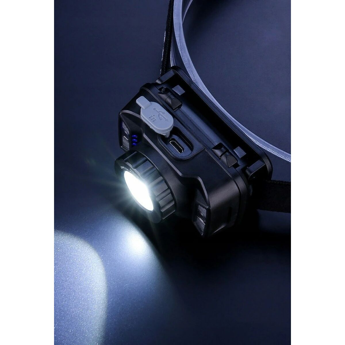 Schwarze Stirnlampe mit hellem weißen Lichtstrahl. Sie hat einen USB-Anschluss und Tasten.
