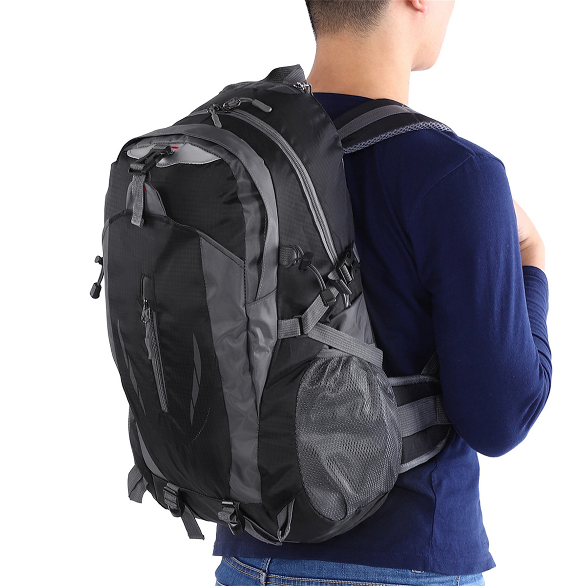 Ein Mann mit einem schwarzen und grauen Rucksack, mit dem Rücken zur Kamera stehend.