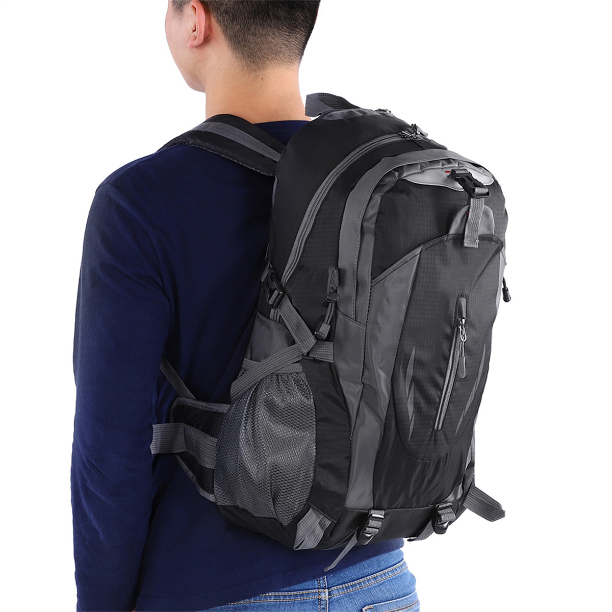 Eine Person mit einem dunkelblauen Hemd und einem schwarzen Rucksack auf dem Rücken.