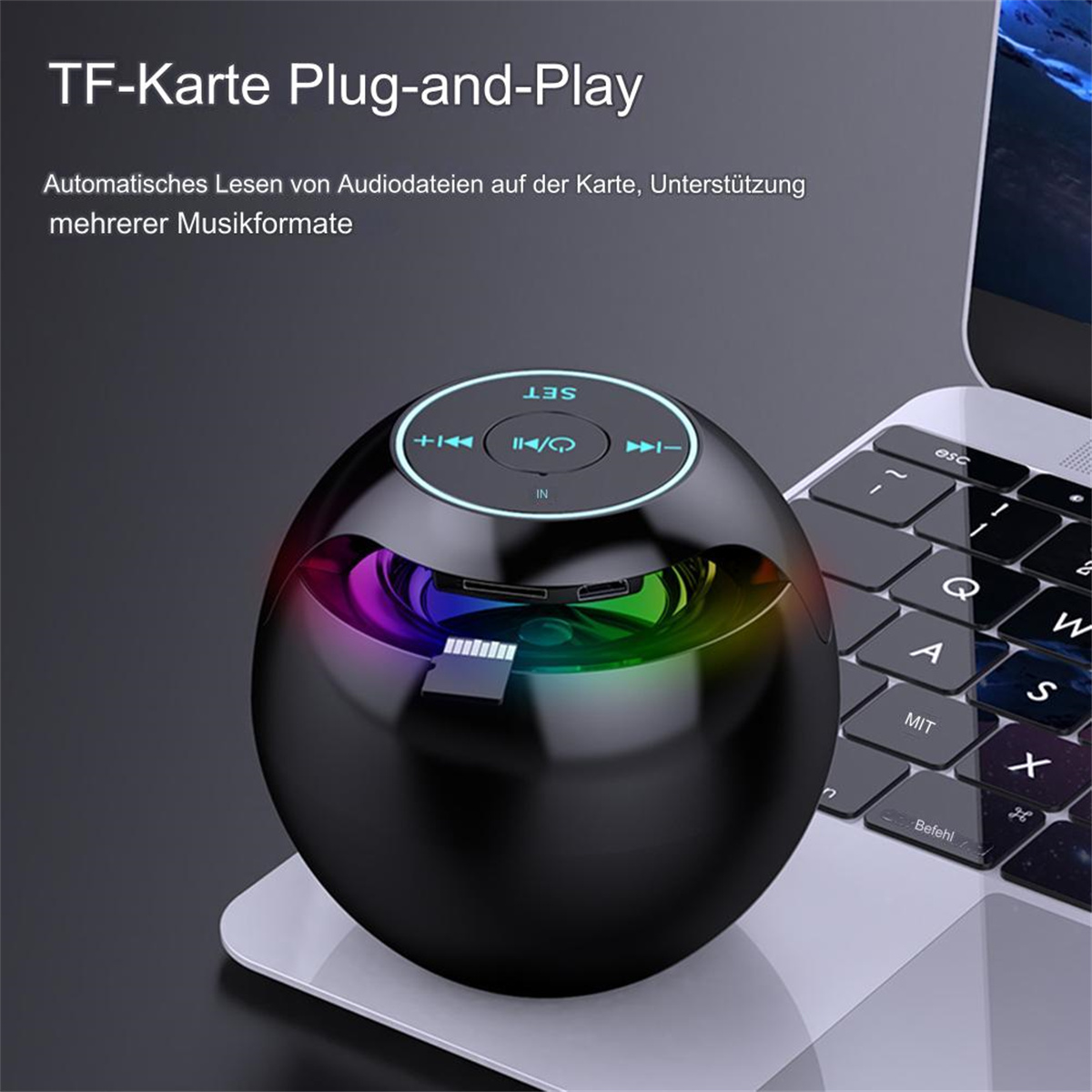 Schwarzer, kugelförmiger Bluetooth-Lautsprecher mit Farbwechsel auf einem Laptop.