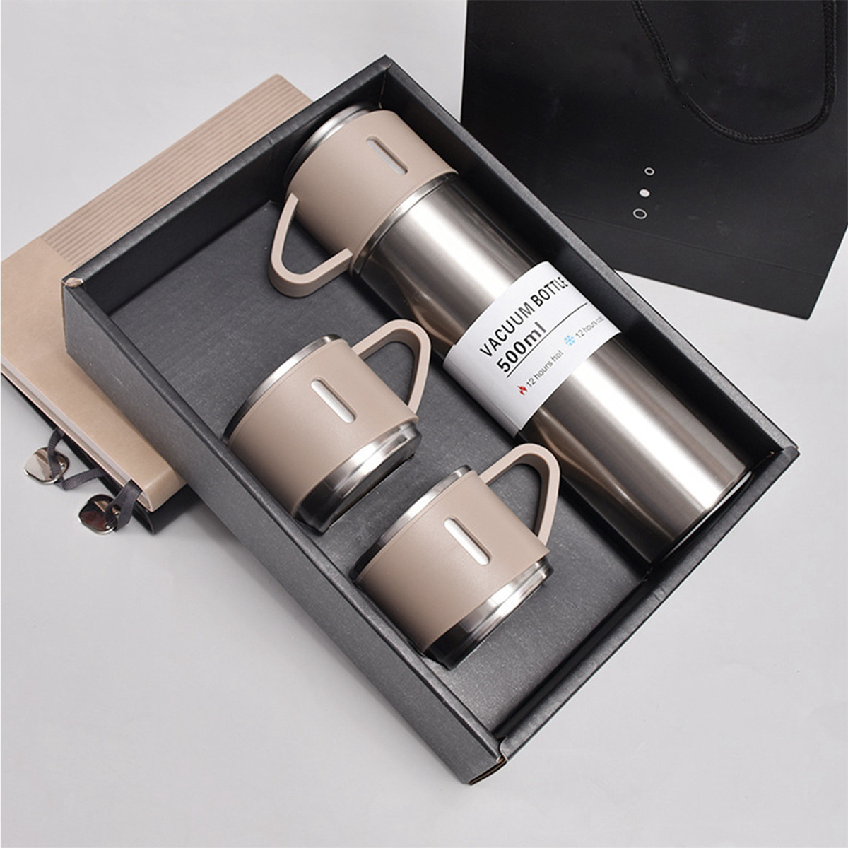 Geschenkset mit Thermoskanne, zwei Bechern in einer schwarzen Box und einem Notizblock.
