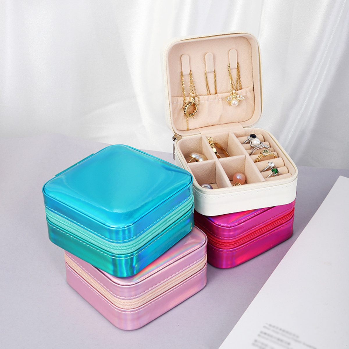 Schmuckkästchen in Blau, Rosa und Weiß, mit geöffneter Box, die Schmuck zeigt. Weißer Hintergrund.