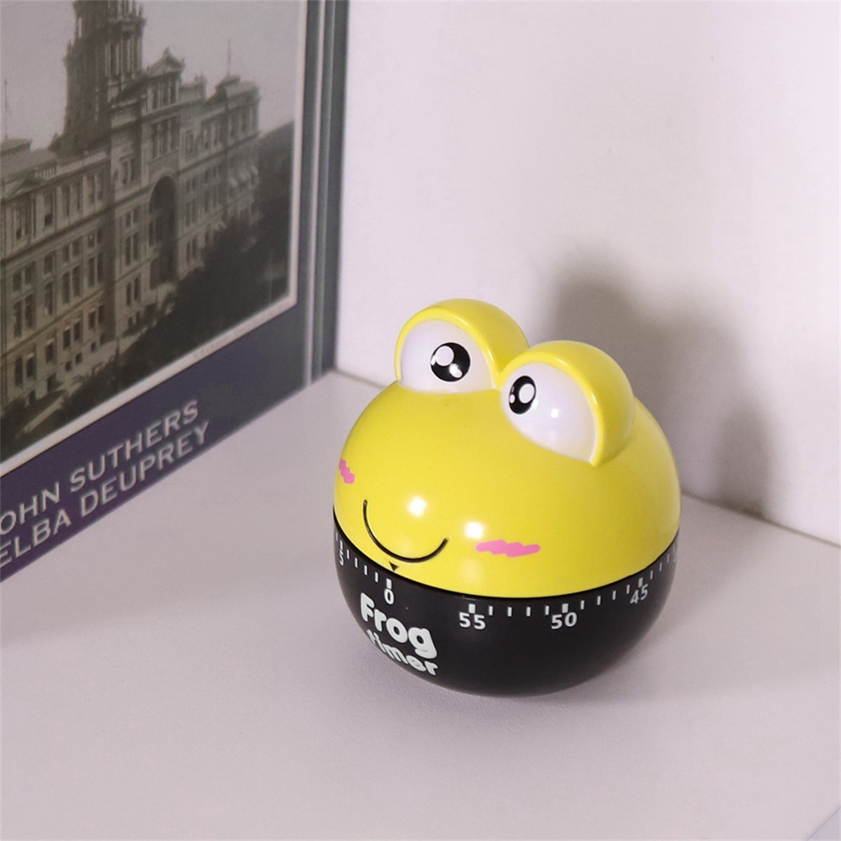Gelber Frosch-Timer mit schwarzer Basis, lächelndem Gesicht und weißen Augen.
