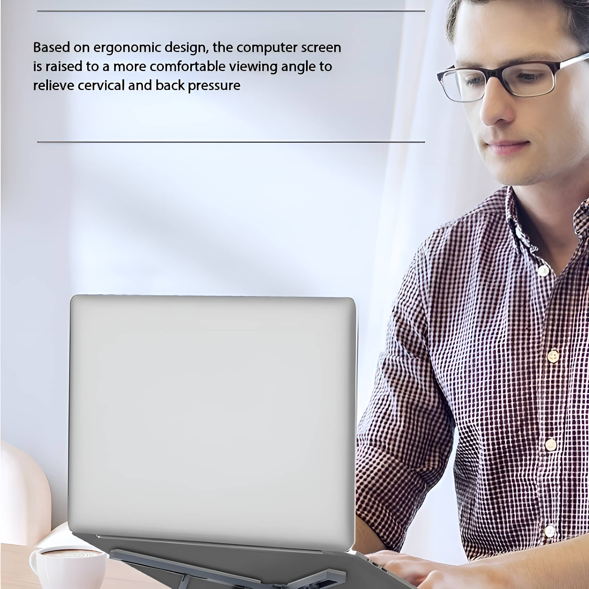 Mann mit Brille arbeitet an einem Laptop, mit Monitor und Schreibtischzubehör.