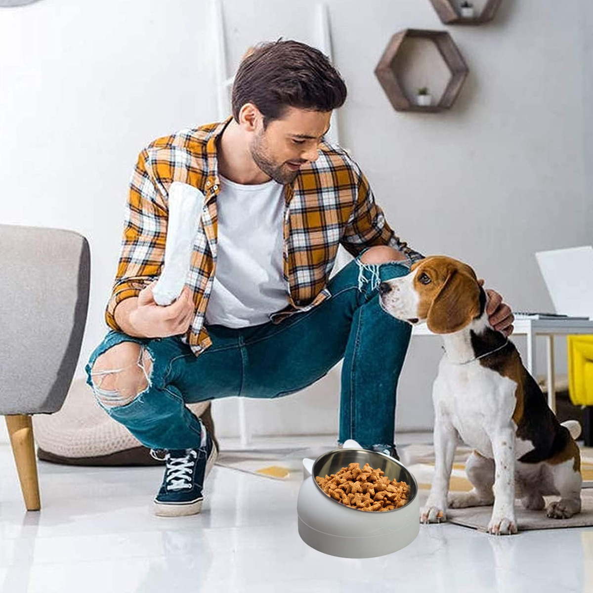 Ein Mann kniet und streichelt einen Beagle neben einem Hundenapf. Die Schüssel enthält Hundefutter. Der Raum hat neutrale Farben.