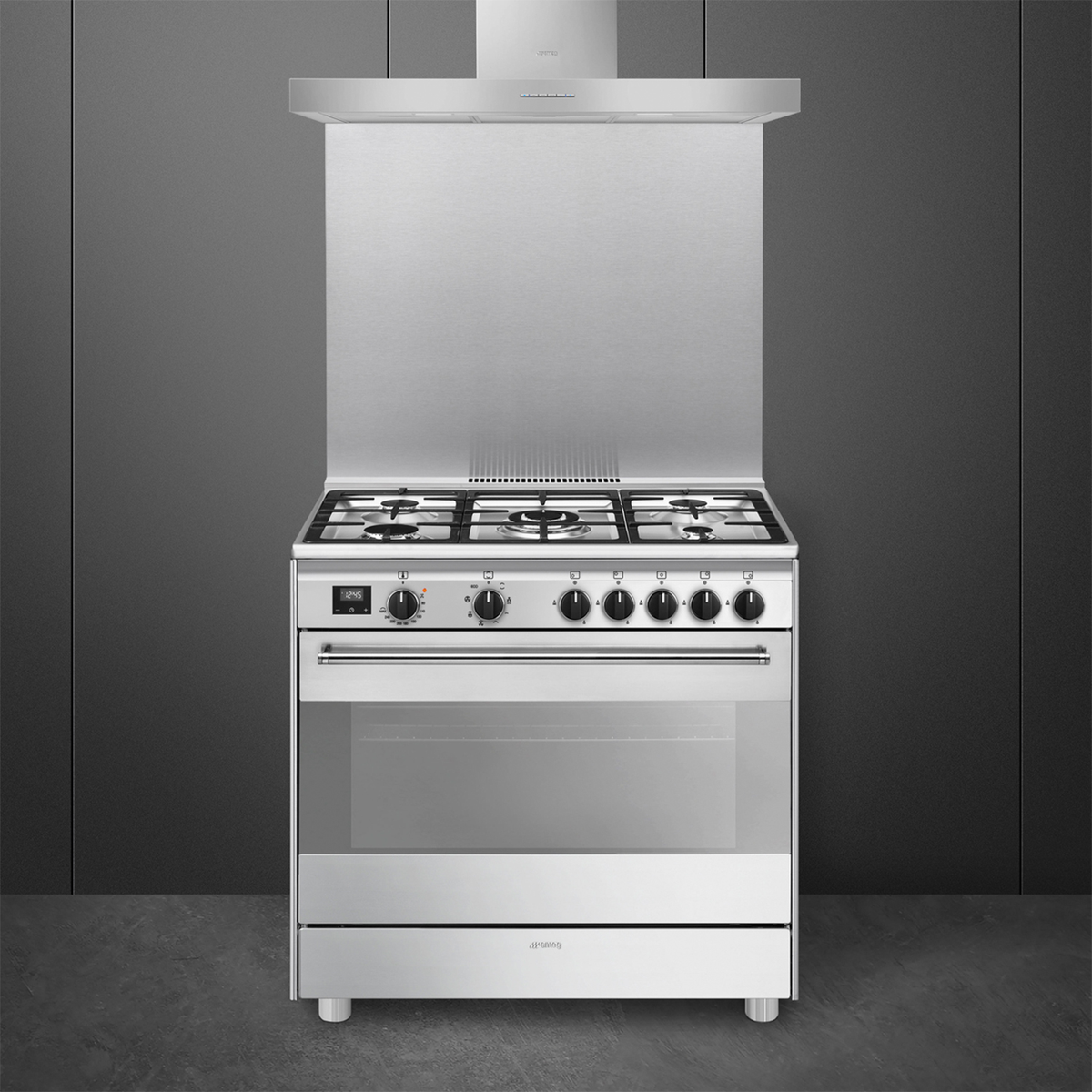 Fornello in acciaio inox con cappa. Ha una porta del forno in vetro e sfondo grigio scuro.