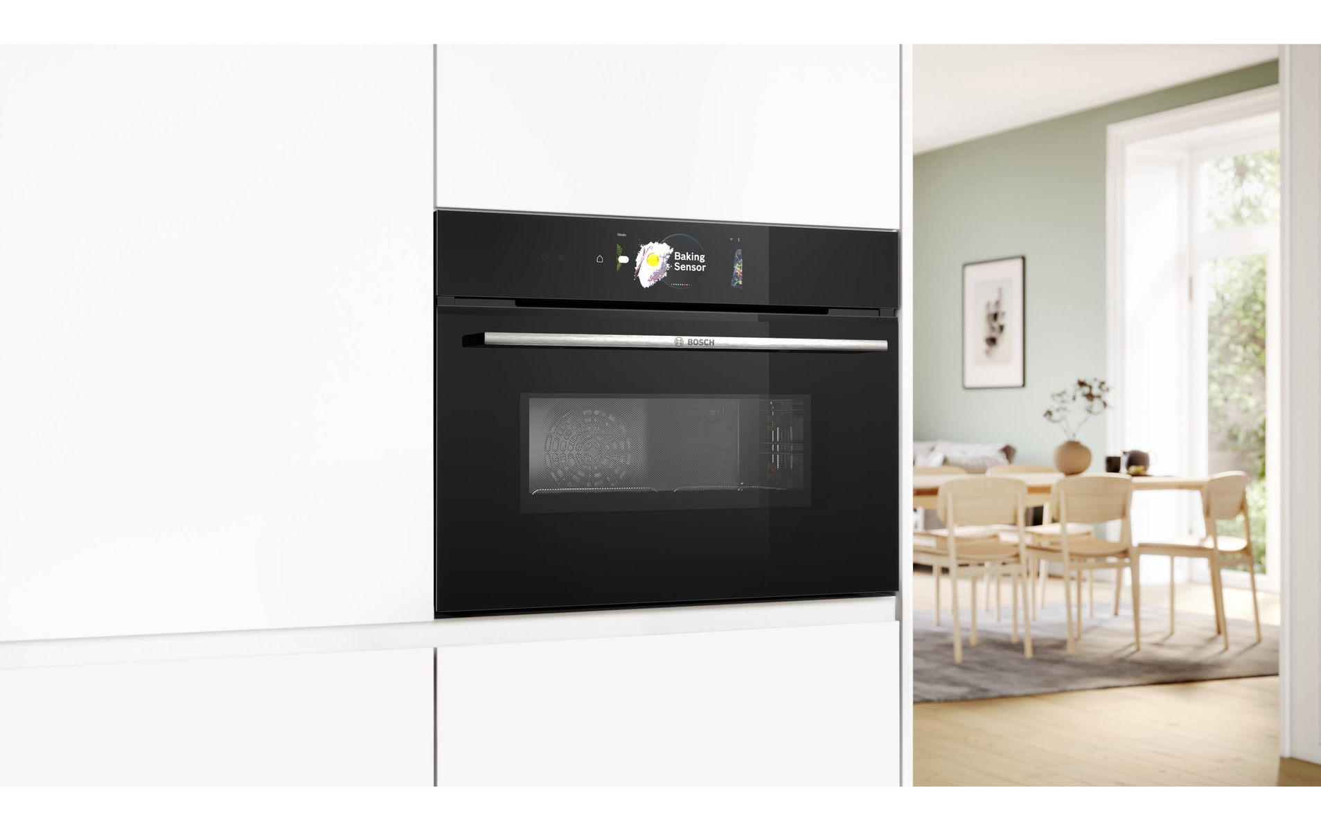 Un forno a microonde nero integrato in un mobile bianco. Una persona è visibile sullo sfondo.