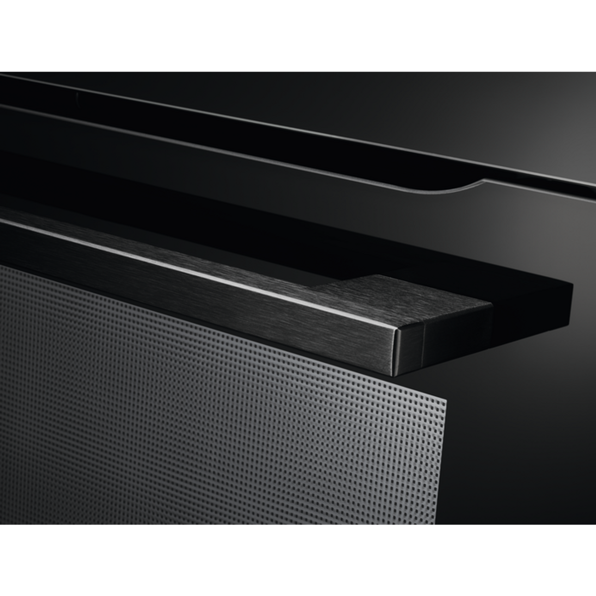 Close-up of a black oven door with a metal mesh. A handle is visible.