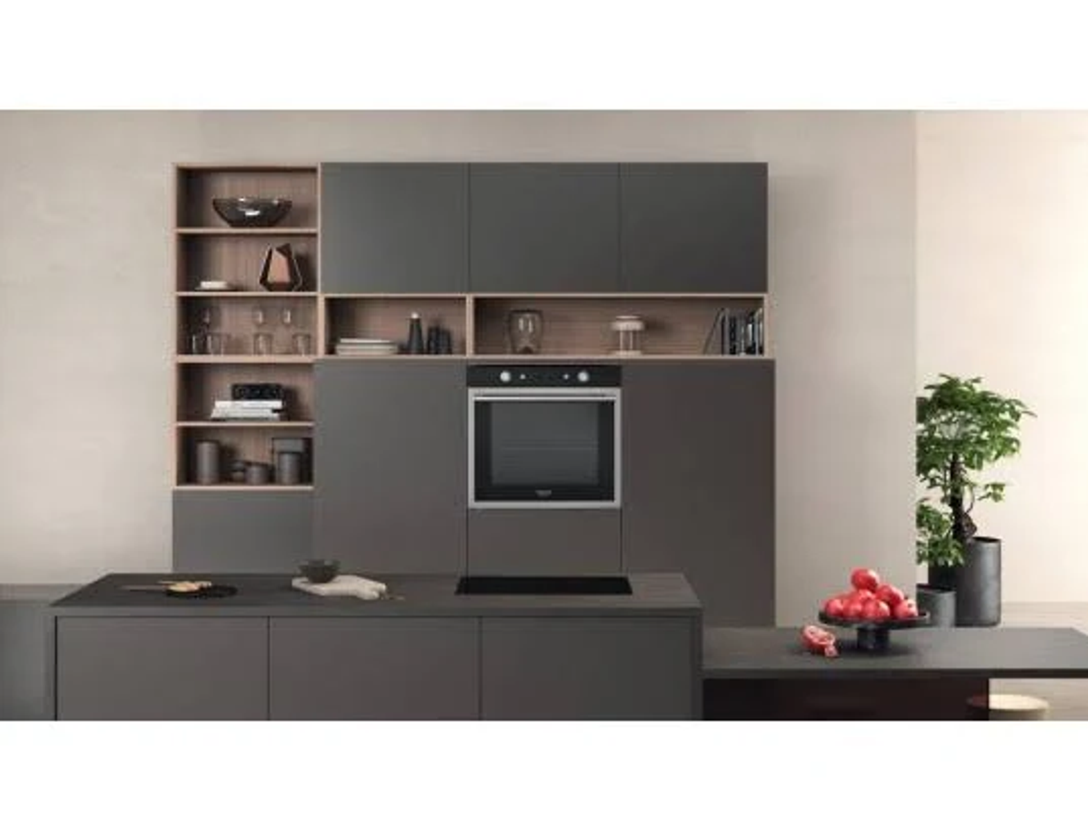 Cocina moderna con armarios grises, horno empotrado y encimera oscura. Hay una planta y elementos decorativos.