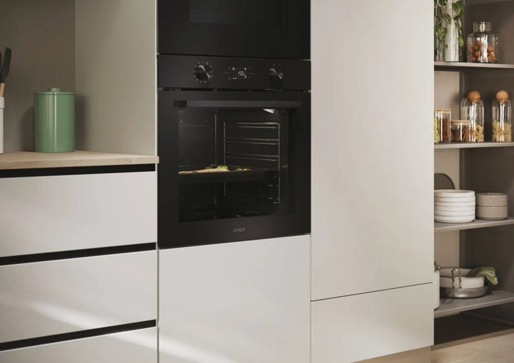 Horno negro integrado en cocina blanca. Puerta cerrada. Marca Candy visible.