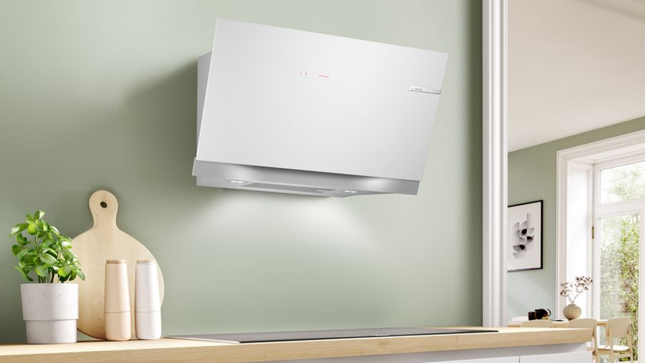 Campana extractora blanca montada en una pared verde con artículos de cocina.