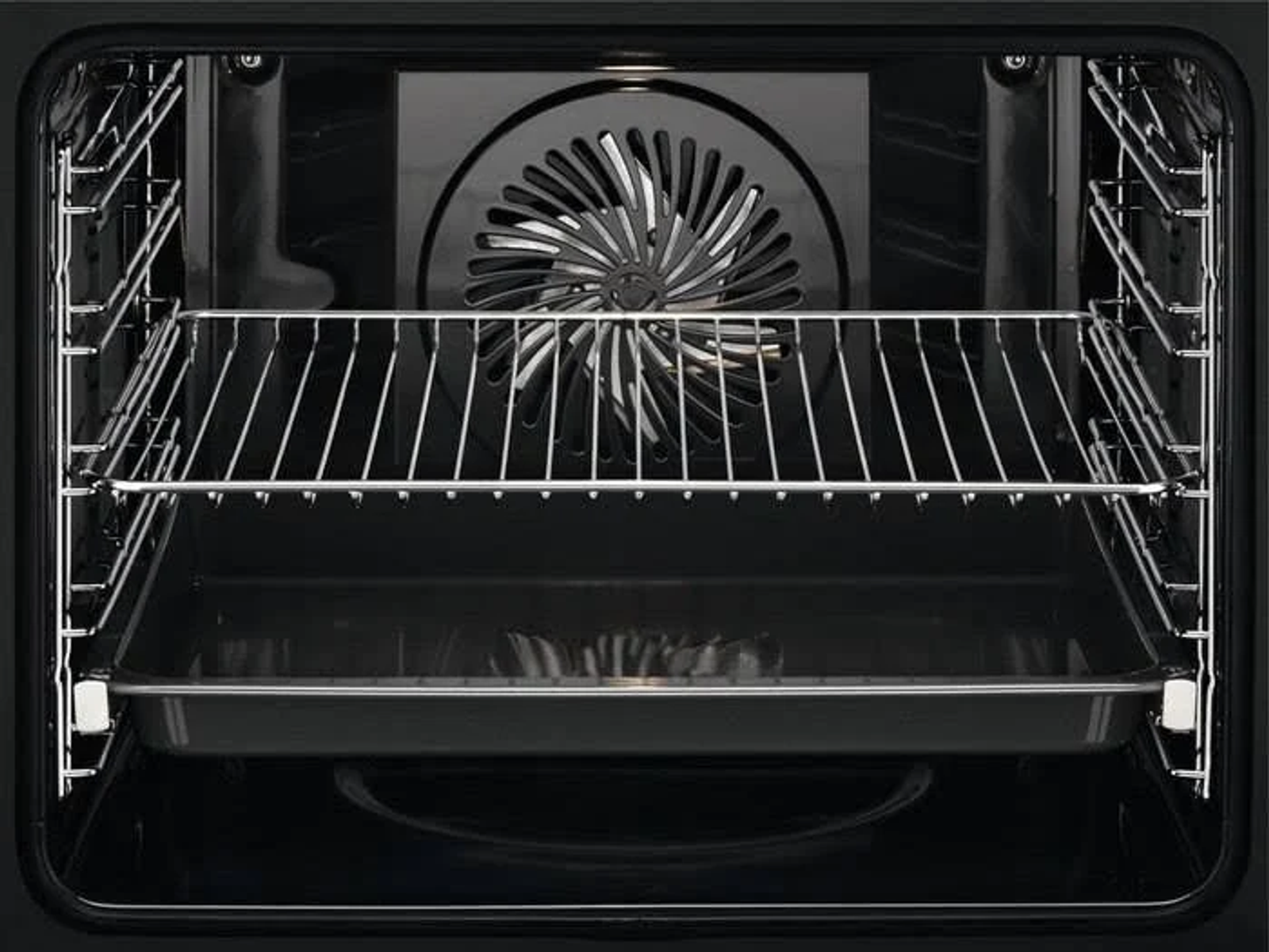 Interior del horno con rejillas, bandeja y un ventilador en la parte trasera. Interior oscuro con metal brillante.