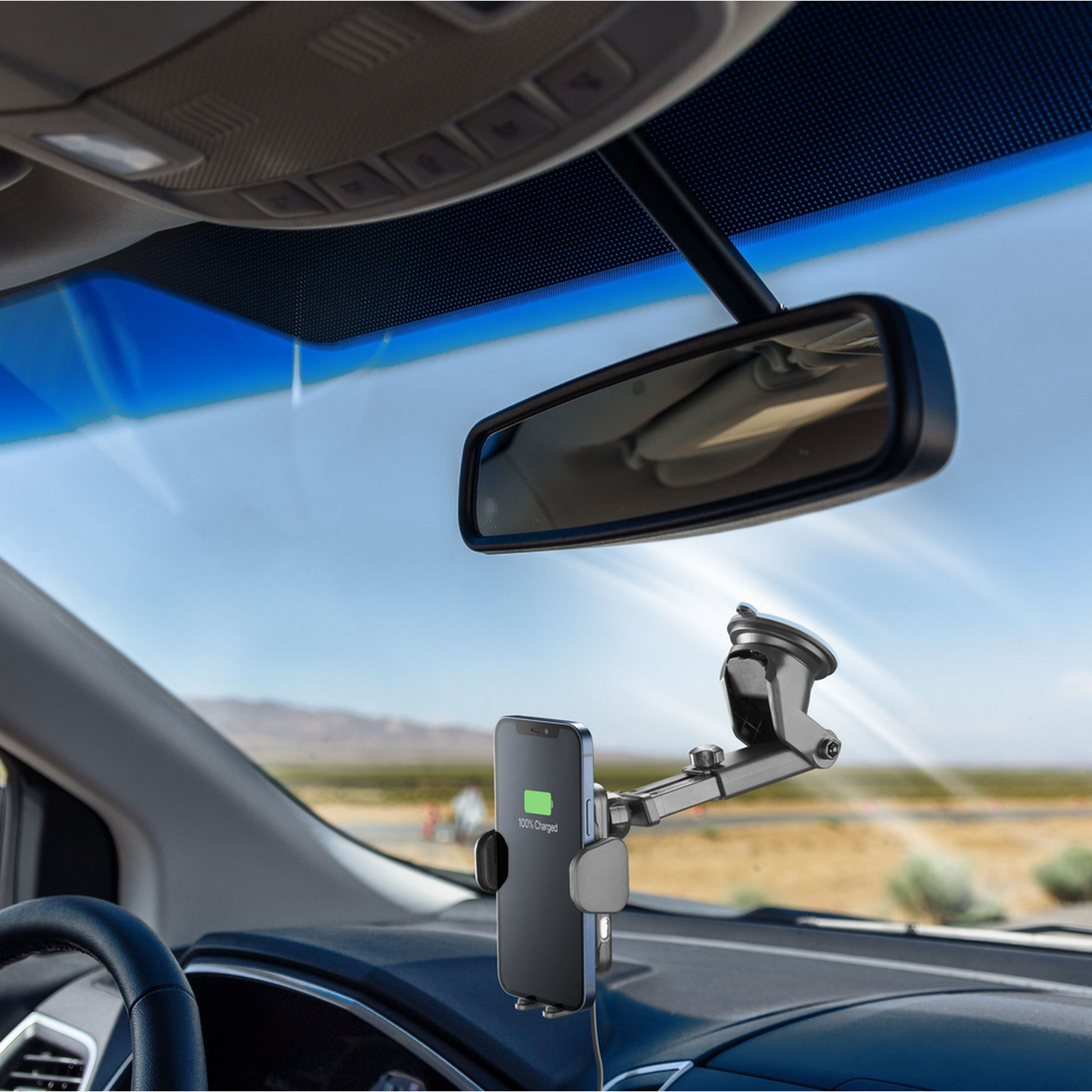 Un smartphone montado en un coche con un cargador. Se ve el salpicadero, la ventana y el espejo.