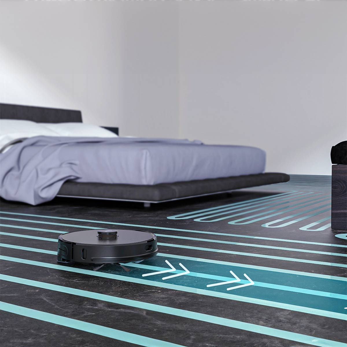 Schwarzer Roboter-Staubsauger auf dunklem Boden mit Pfeilen, Bett im Hintergrund.