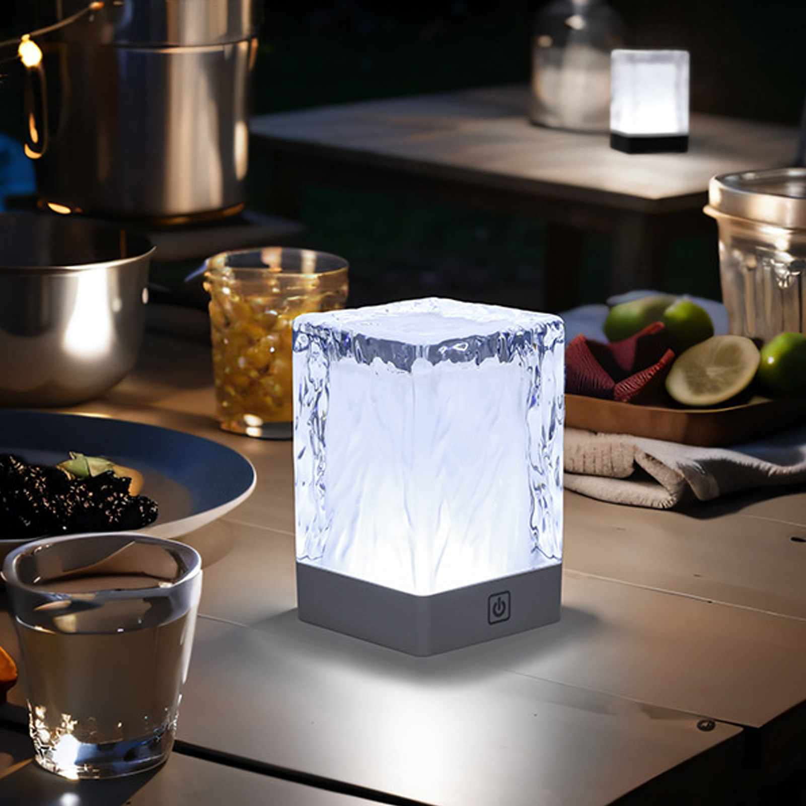 Leuchtende würfelförmige Lampe auf einem Holztisch mit anderen Gegenständen, draußen bei Nacht.