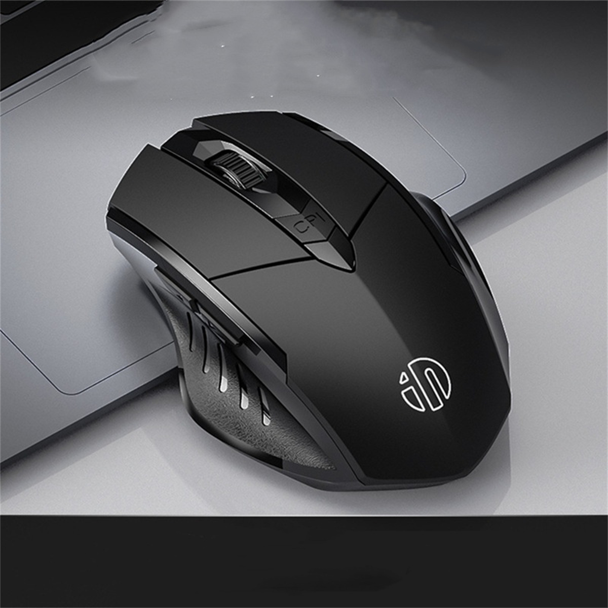 Eine schwarze kabellose Maus auf einem silbernen Laptop. Die Maus hat ein schlankes Design.