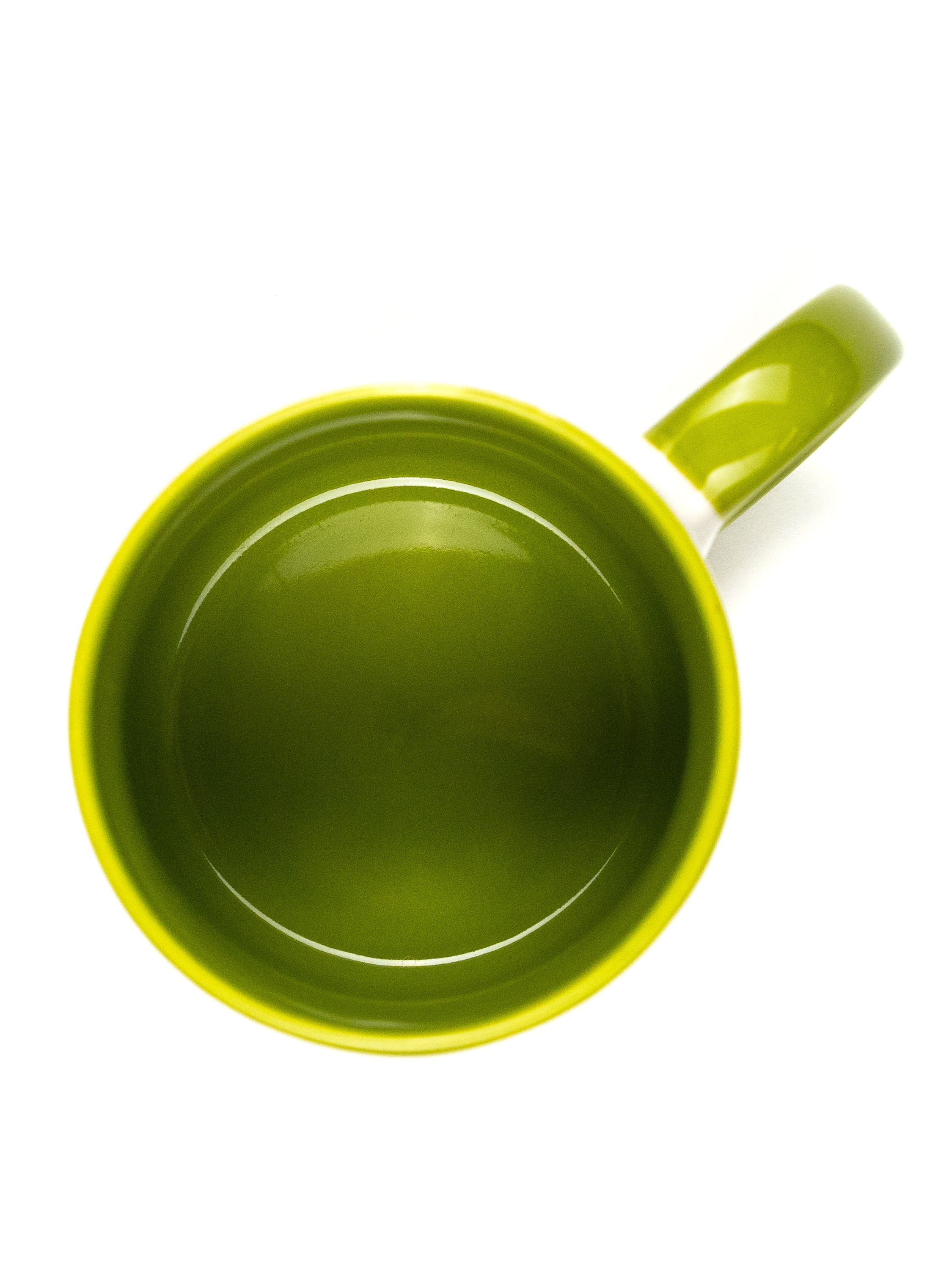 Draufsicht auf eine grüne Tasse mit weißem Innenraum und grünem Henkel, isoliert auf Weiß.