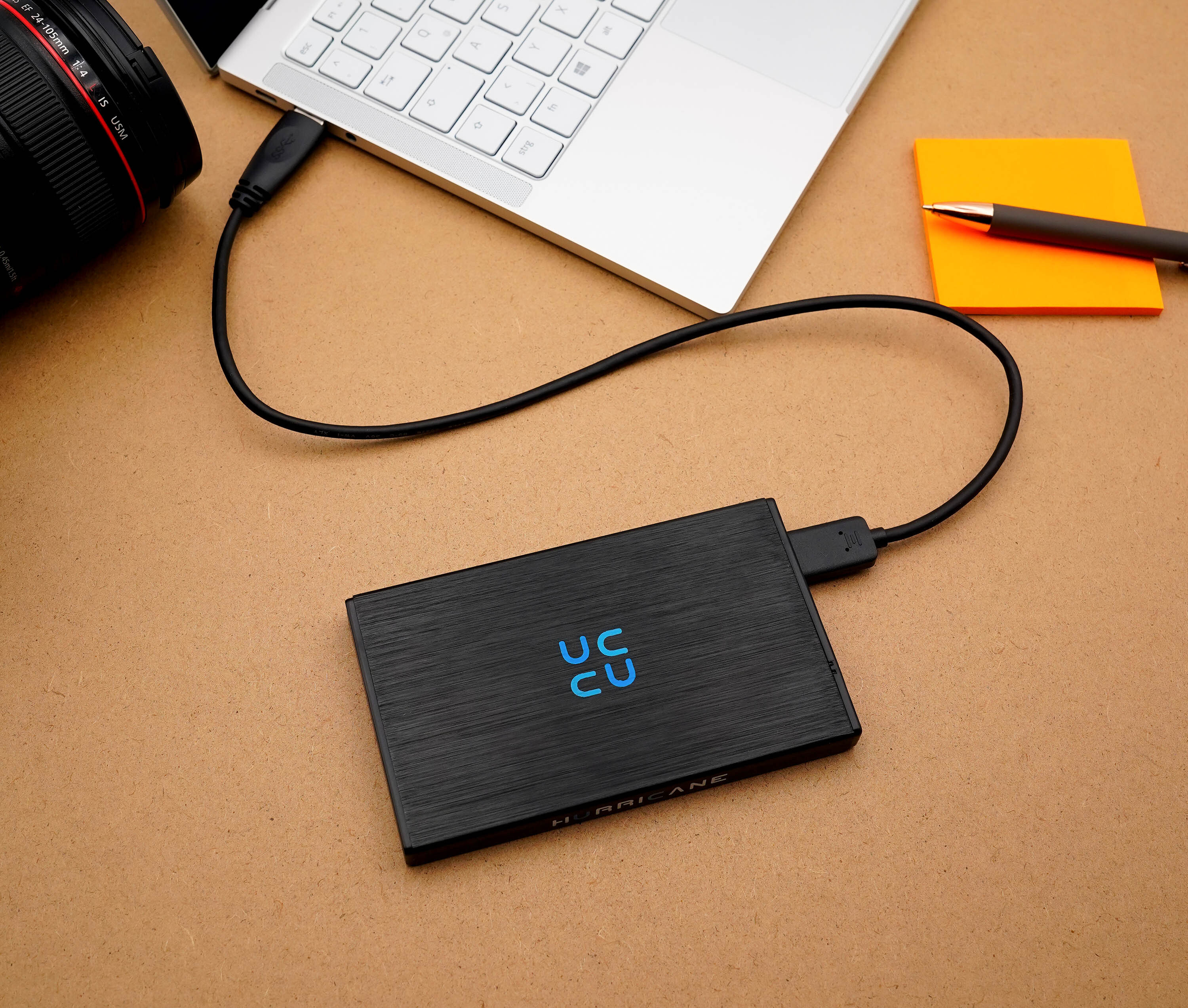 Eine schwarze externe Festplatte, verbunden mit einem silbernen Laptop über ein schwarzes USB-Kabel.