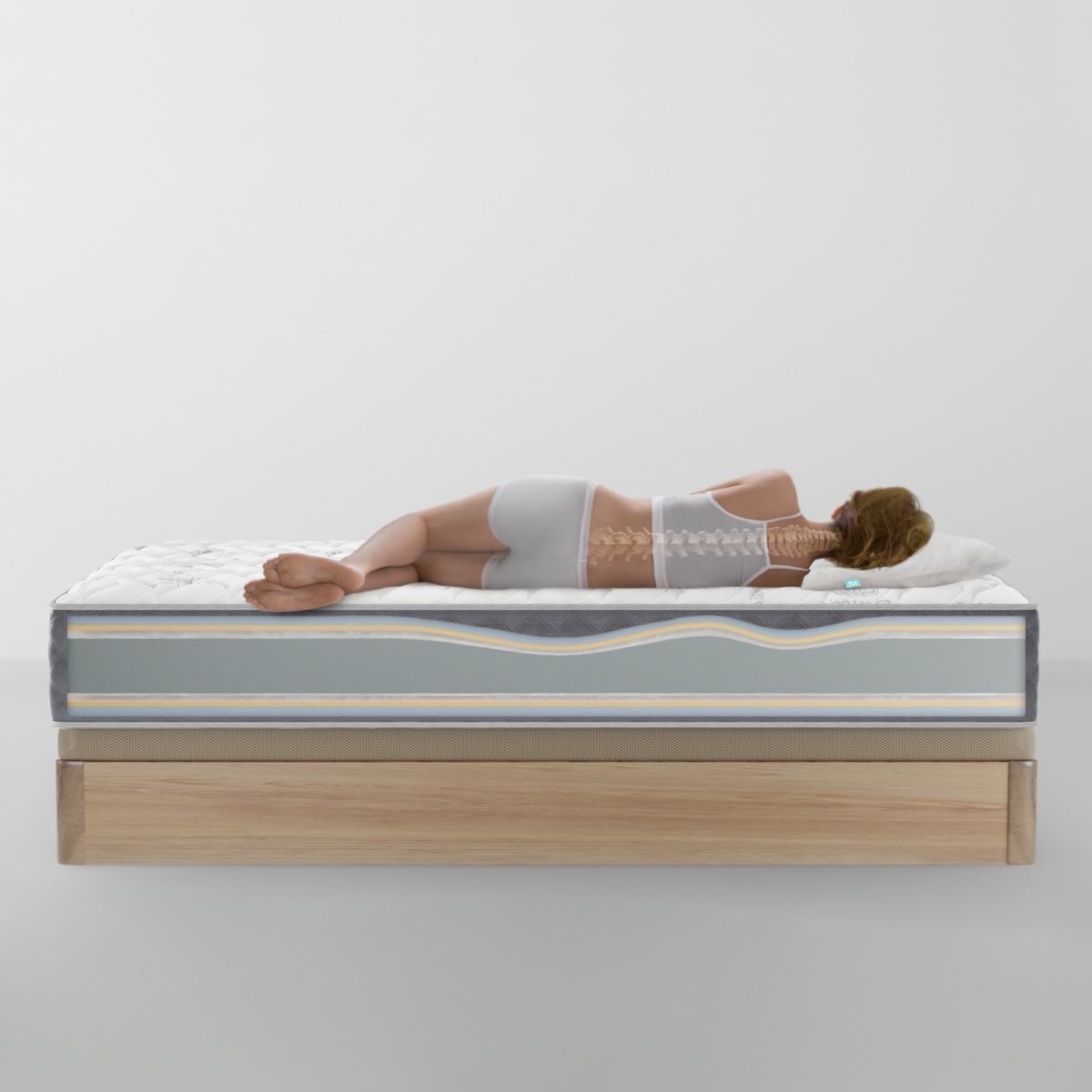 Mujer acostada en un colchón. El esqueleto es visible. El colchón está sobre una base de madera.