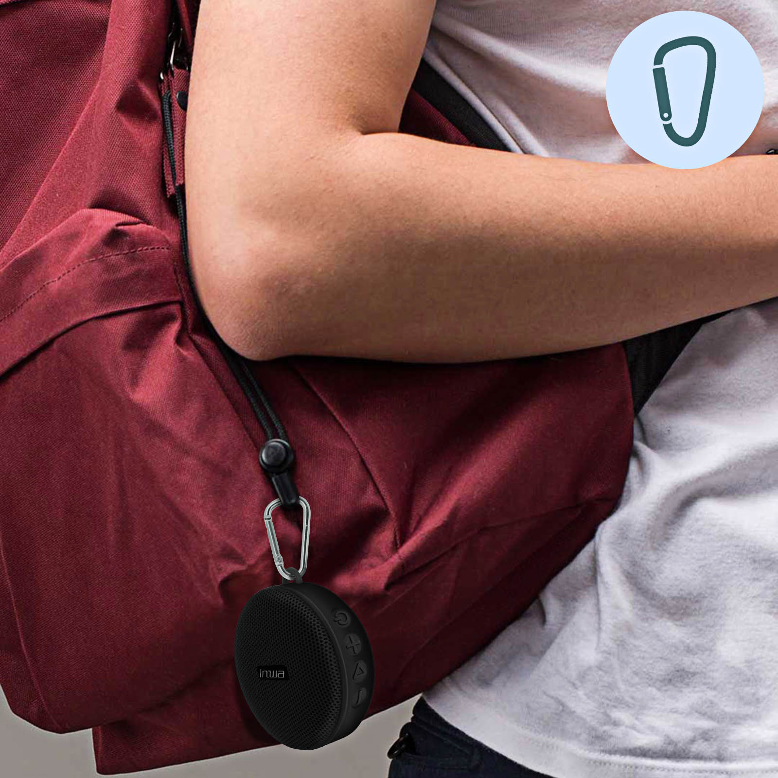 Le bras d'une personne avec un haut-parleur noir attaché à un sac à dos via un mousqueton.