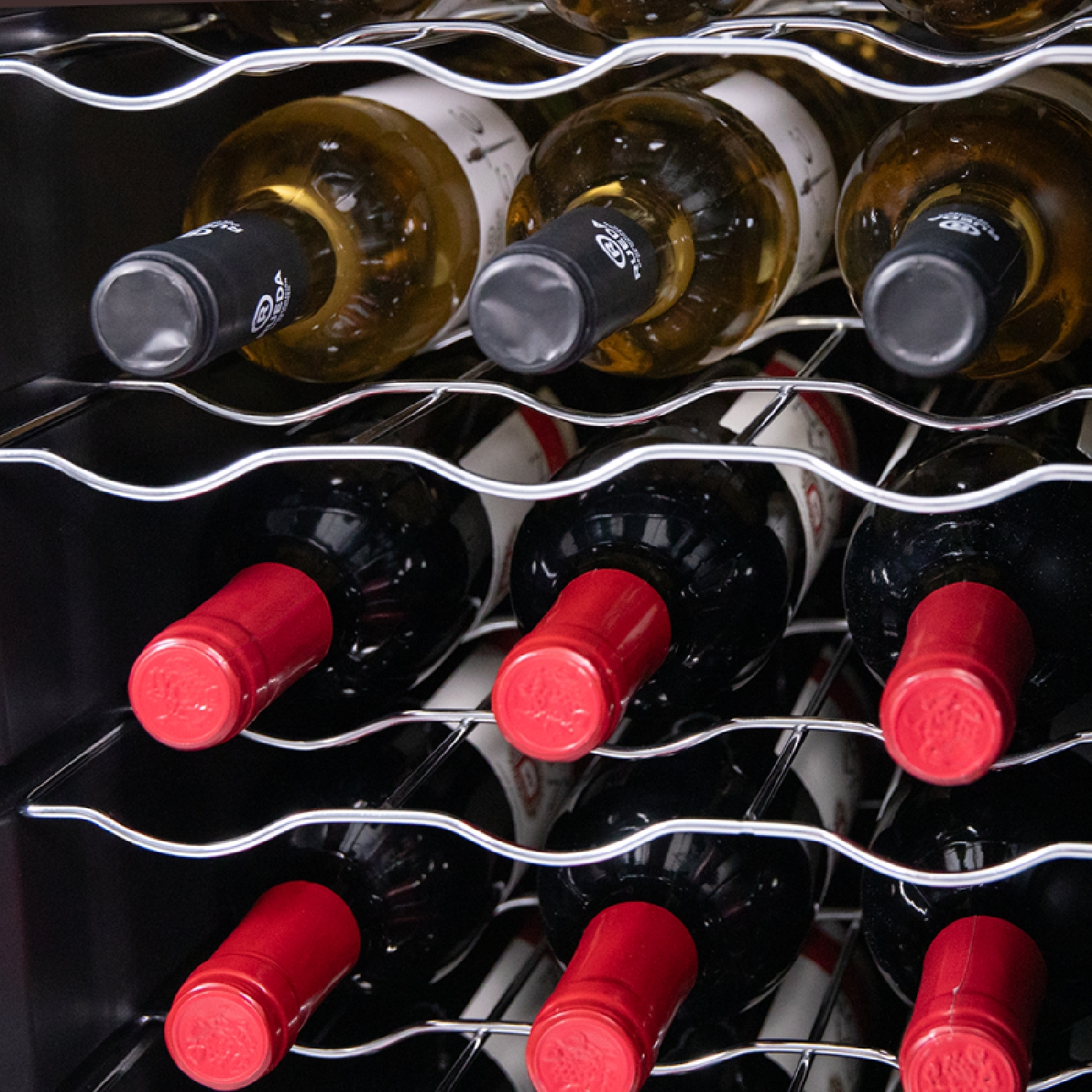 Wine bottles in a wine cooler. Red and white wine bottles. Close-up view with a dark interior.