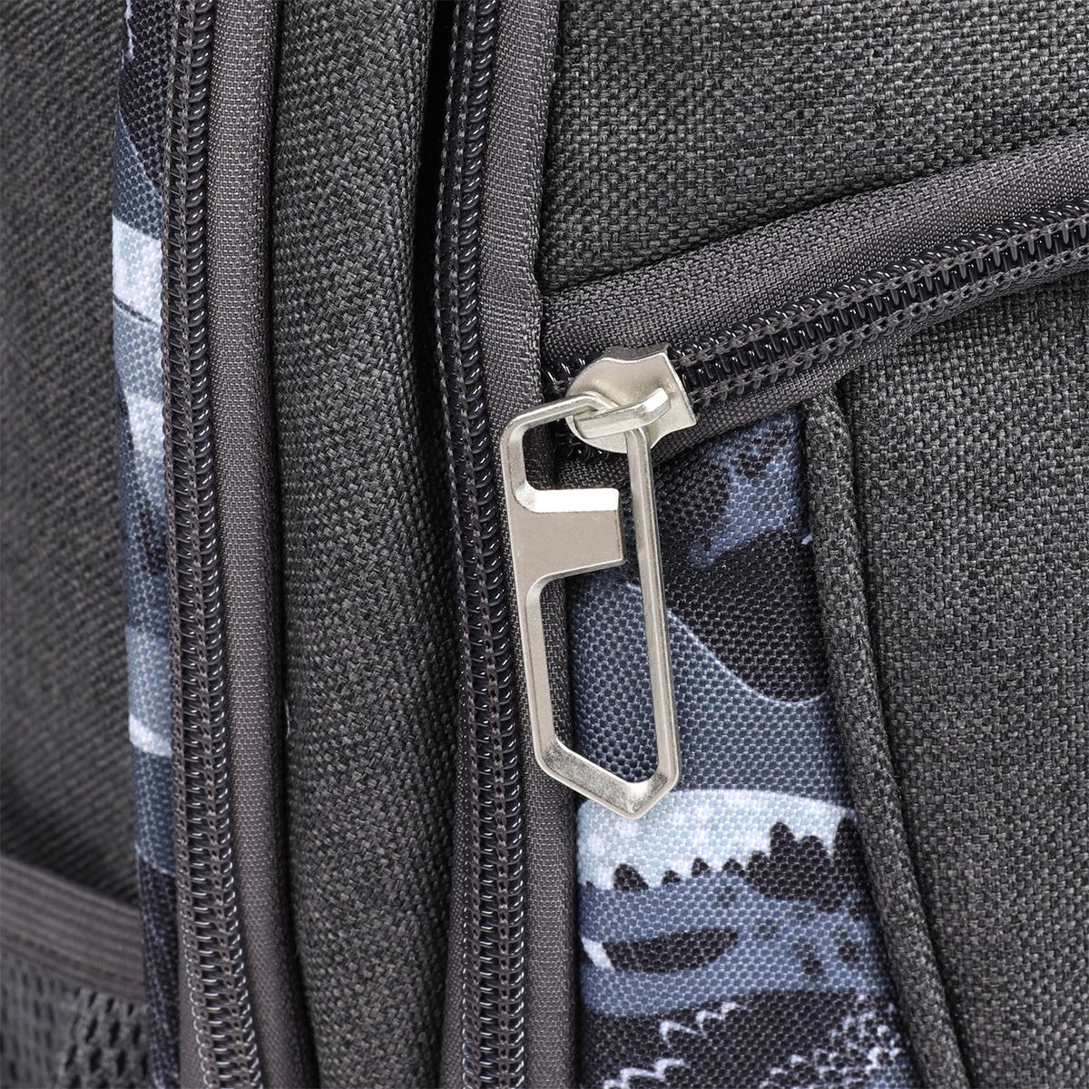 Nahaufnahme eines Rucksackreißverschlusses. Der Reißverschluss ist silberfarben, der Rucksack hat ein Tarnmuster.