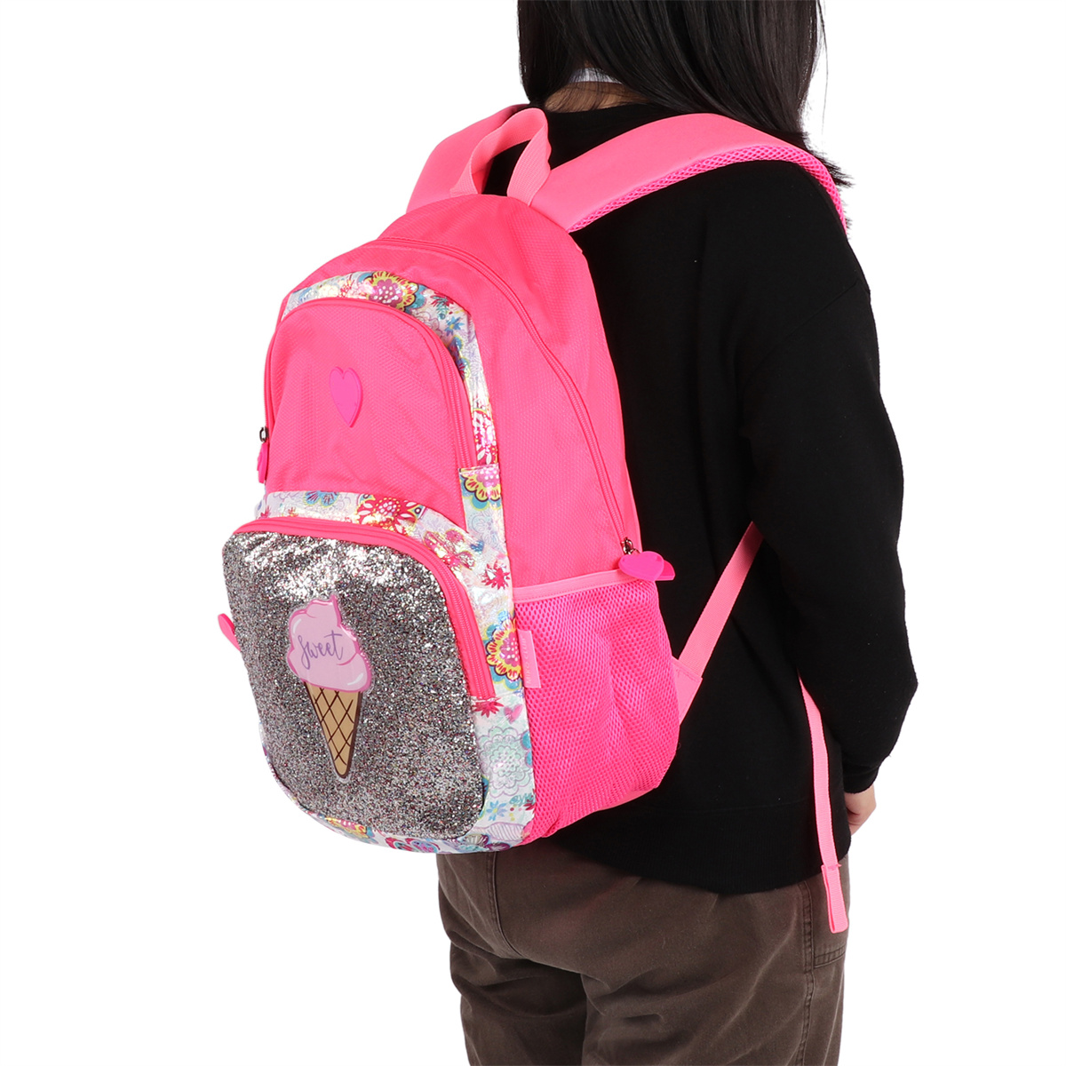 Ein pinkfarbener Rucksack mit Eiscreme-Design, getragen von einer Person. Schwarzes Hemd und braune Hose.