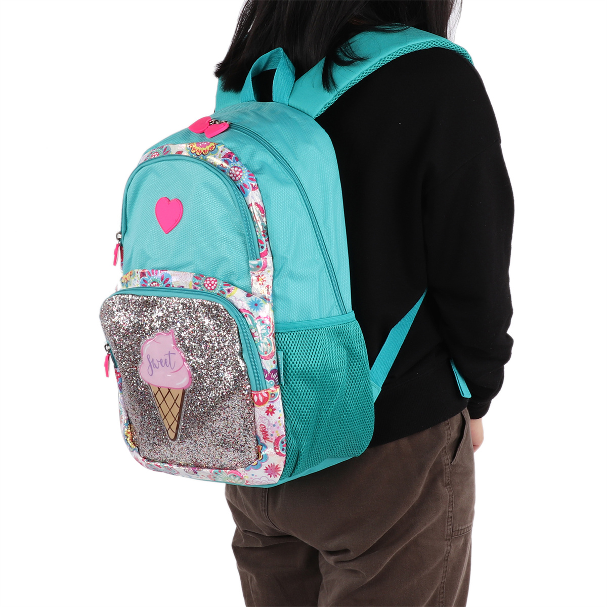Ein Mädchen trägt einen türkisblauen Rucksack mit einem Eiswaffel-Design. Der Rucksack ist auf ihrem Rücken.