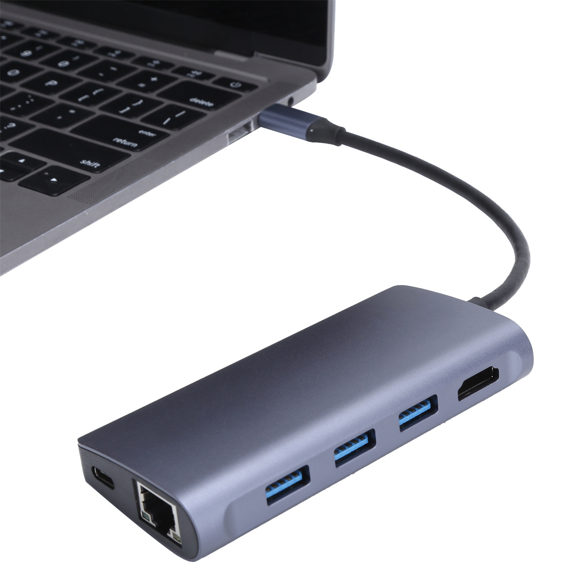 Ein silbergrauer Hub mit mehreren Anschlüssen, die mit einem Laptop verbunden sind. Schwarzes Kabel.