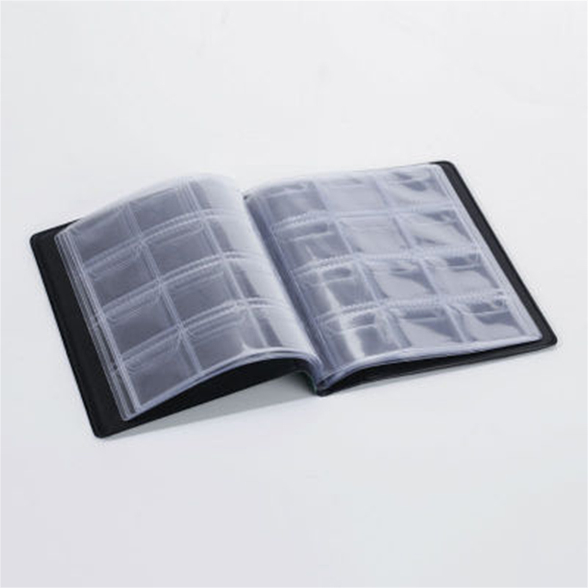 Offenes Münzalbum mit transparenten Taschen auf weißer Oberfläche.