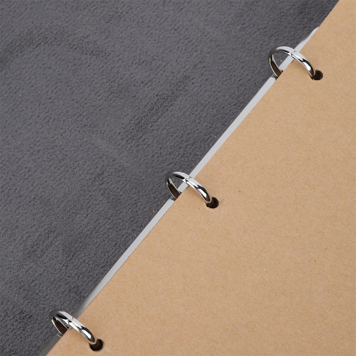Nahaufnahme eines Notizbuchs mit drei Metallringen. Die Seiten sind beige und grau.