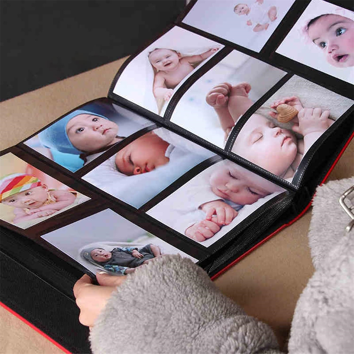 Ein geöffnetes Fotoalbum, das mehrere Babyfotos zeigt. Eine Hand hält das Album.