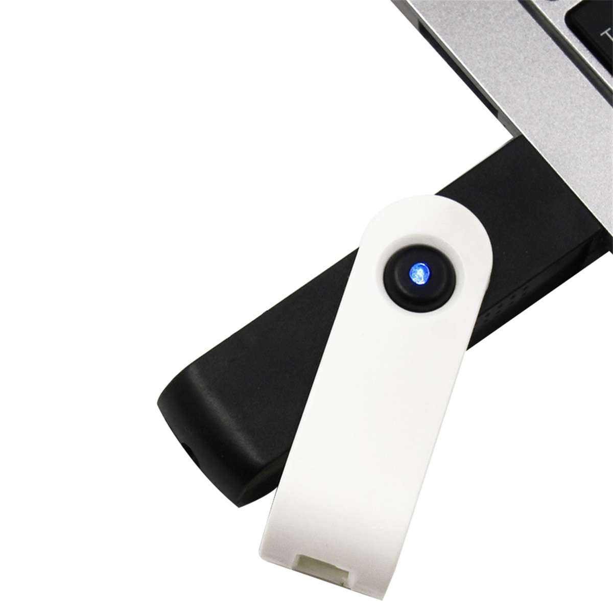 Ein weißer und schwarzer USB-Stick, der in einen Laptop gesteckt wird, mit blauem Licht.