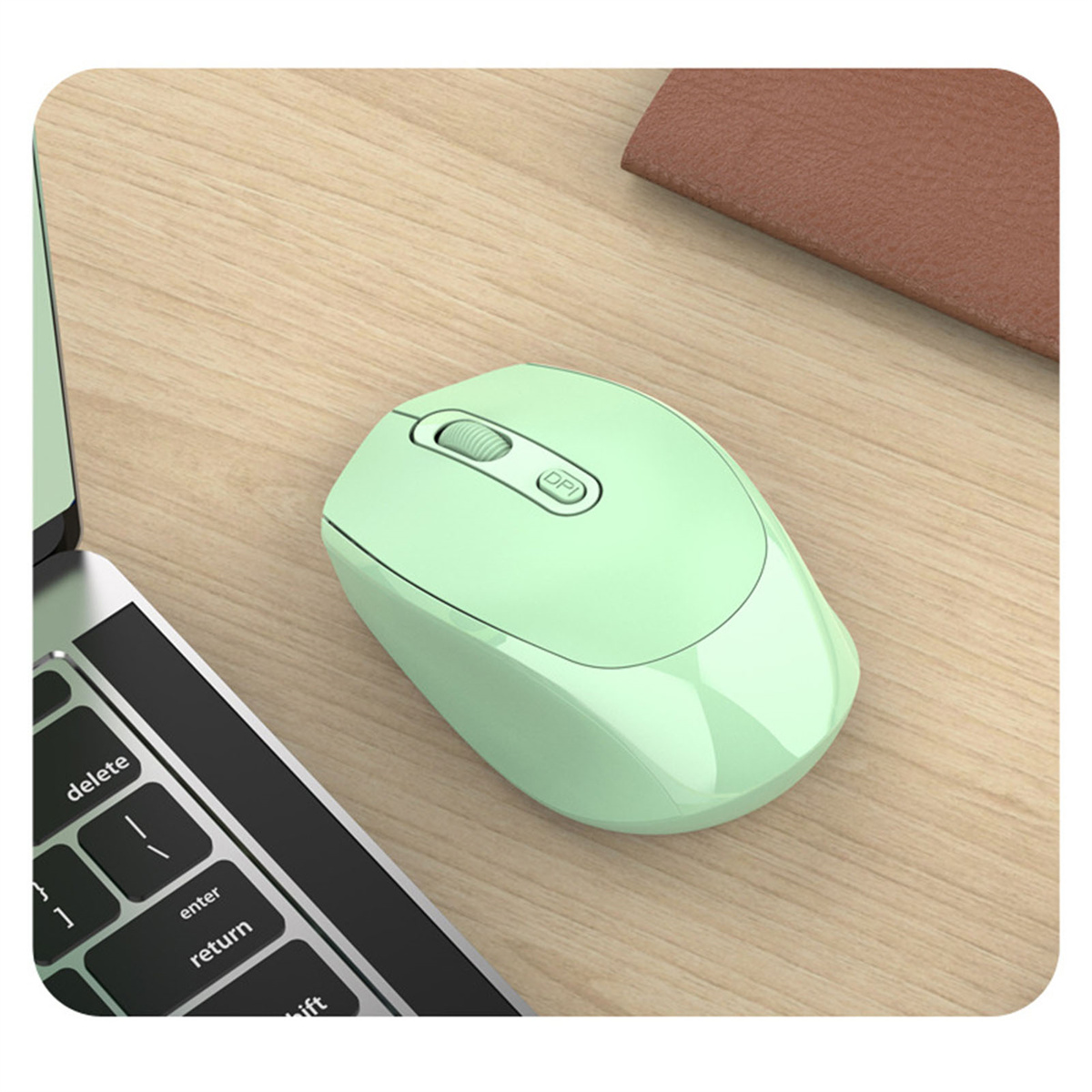 Grüne kabellose Maus auf einem Holzschreibtisch neben einer Laptop-Tastatur.