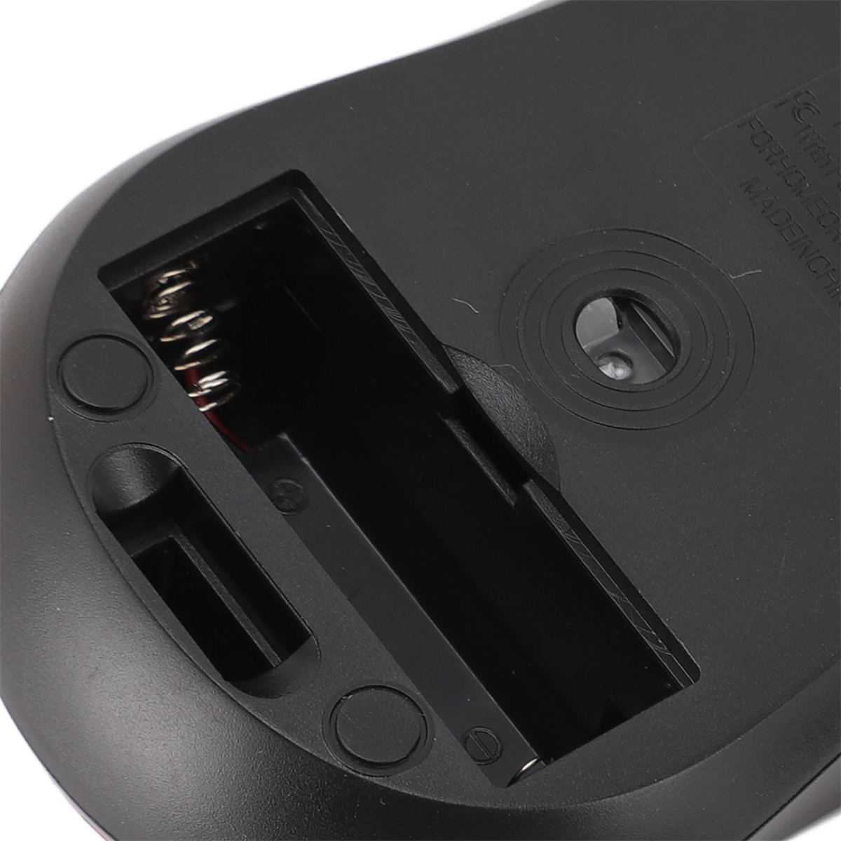 Der Boden eines schwarzen Geräts mit Batteriefach. Eine silberne Feder ist sichtbar.